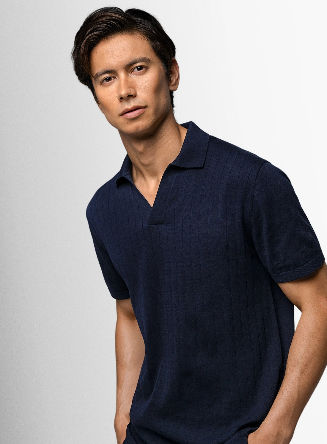 Man wearing a navy blue polo shirt against a light gray background