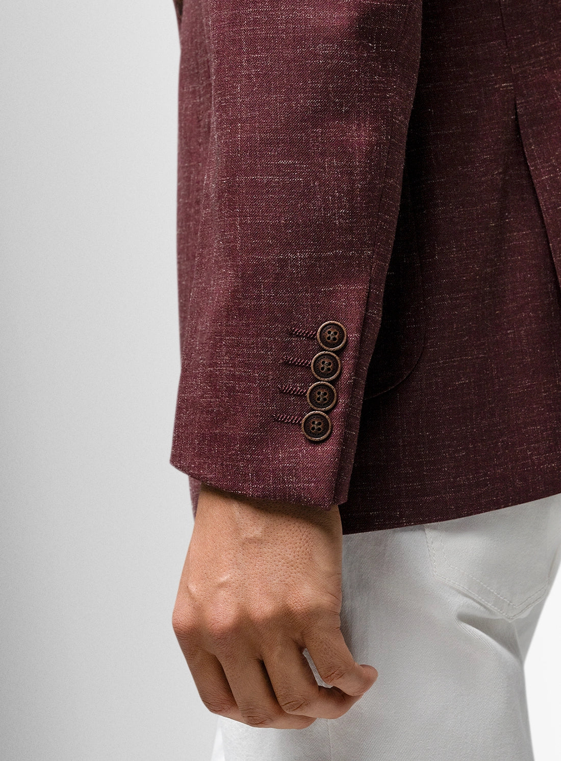 Close-up of a maroon suit jacket with buttons on a white background