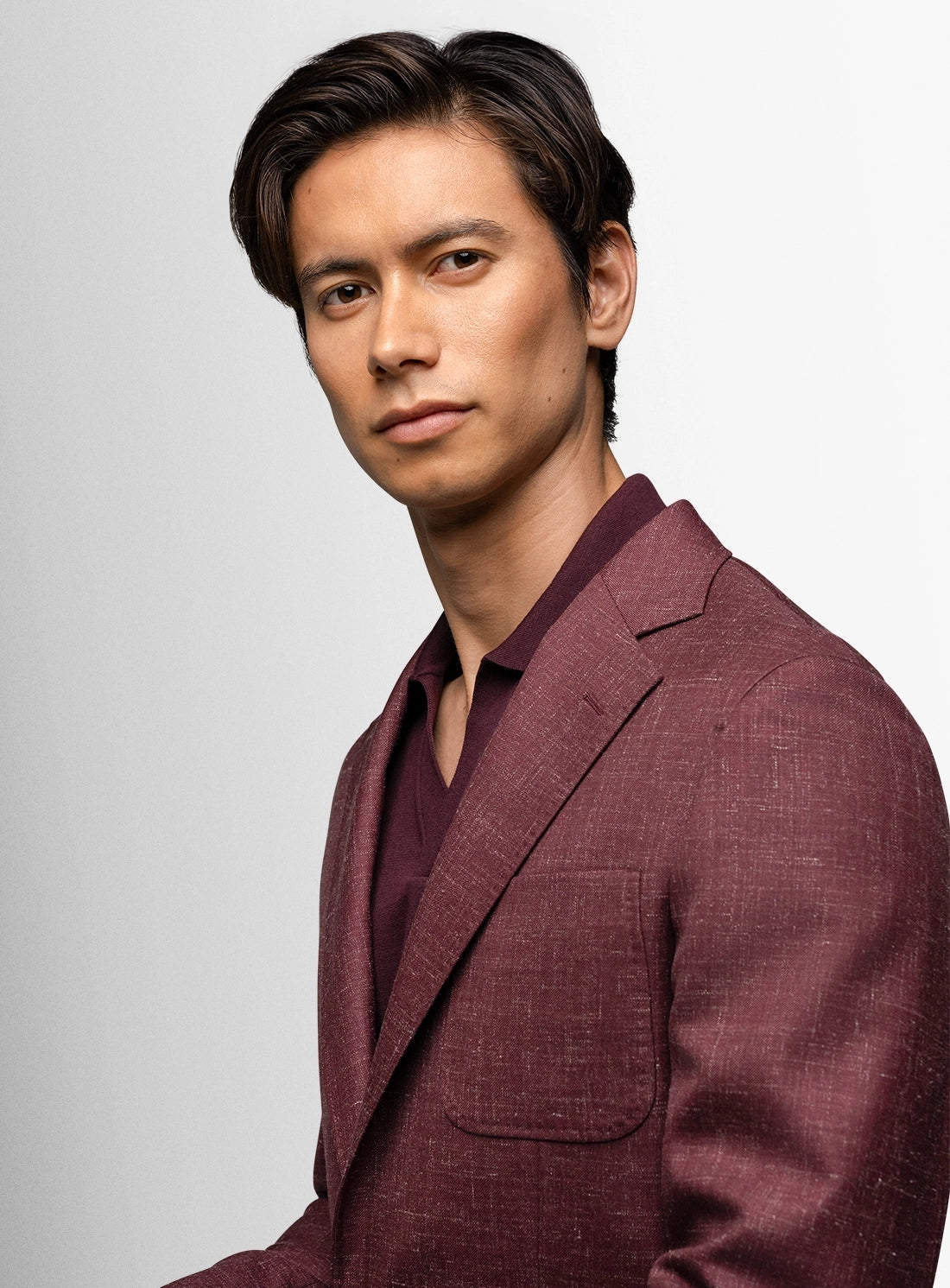 Man wearing a maroon suit against a light gray background