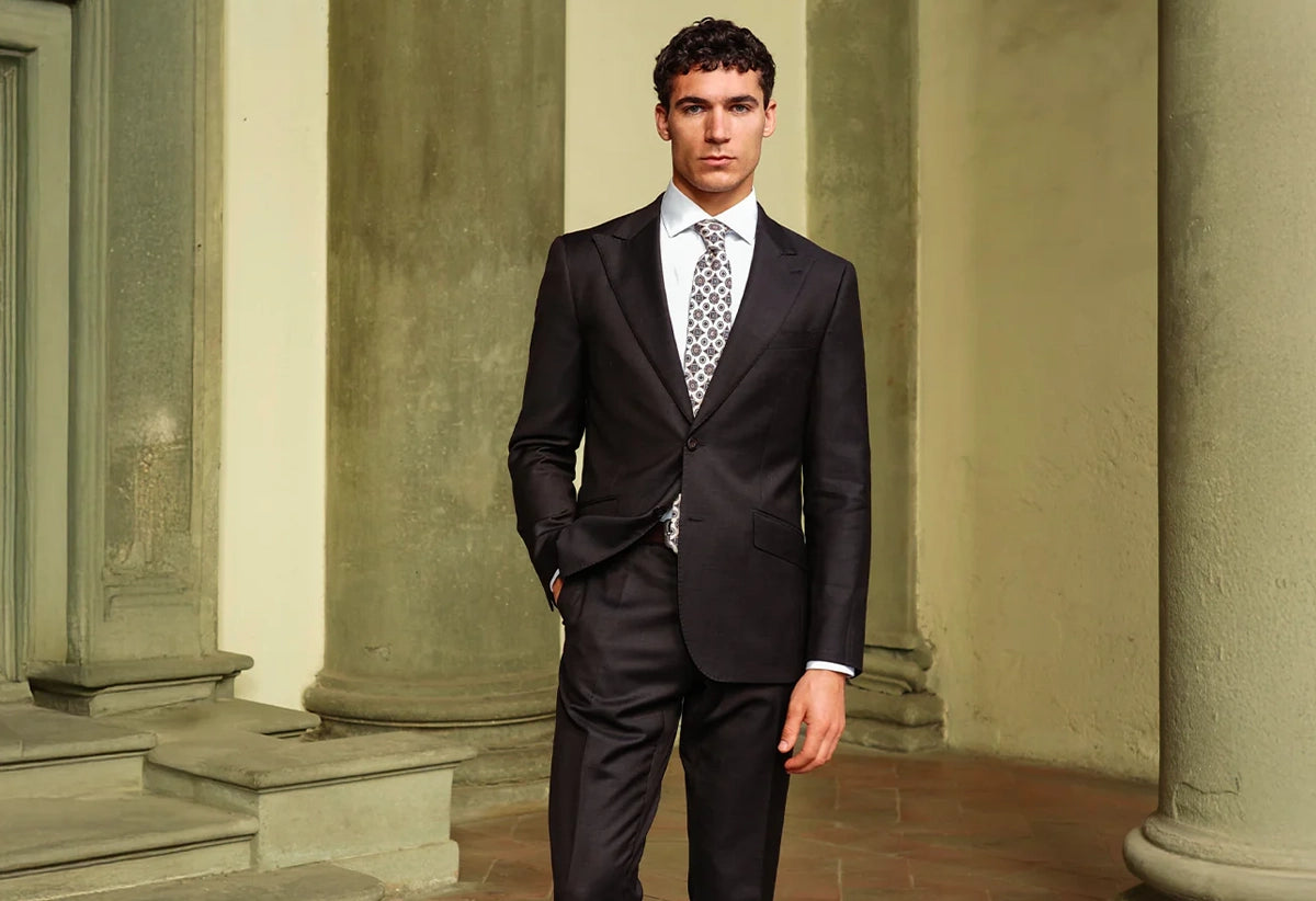 Man in a black suit standing in front of classical architecture