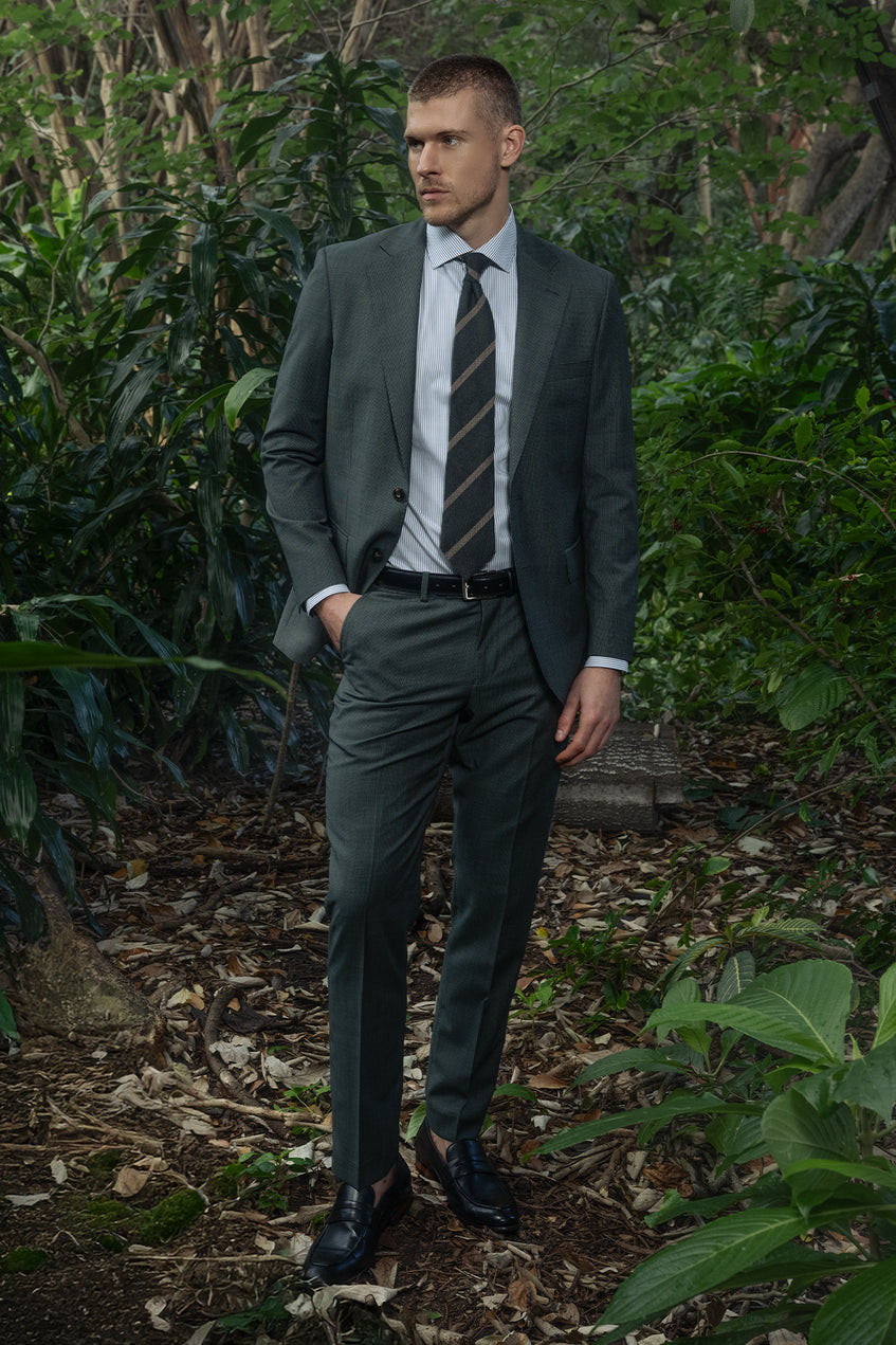 Man in a suit standing in a forest setting