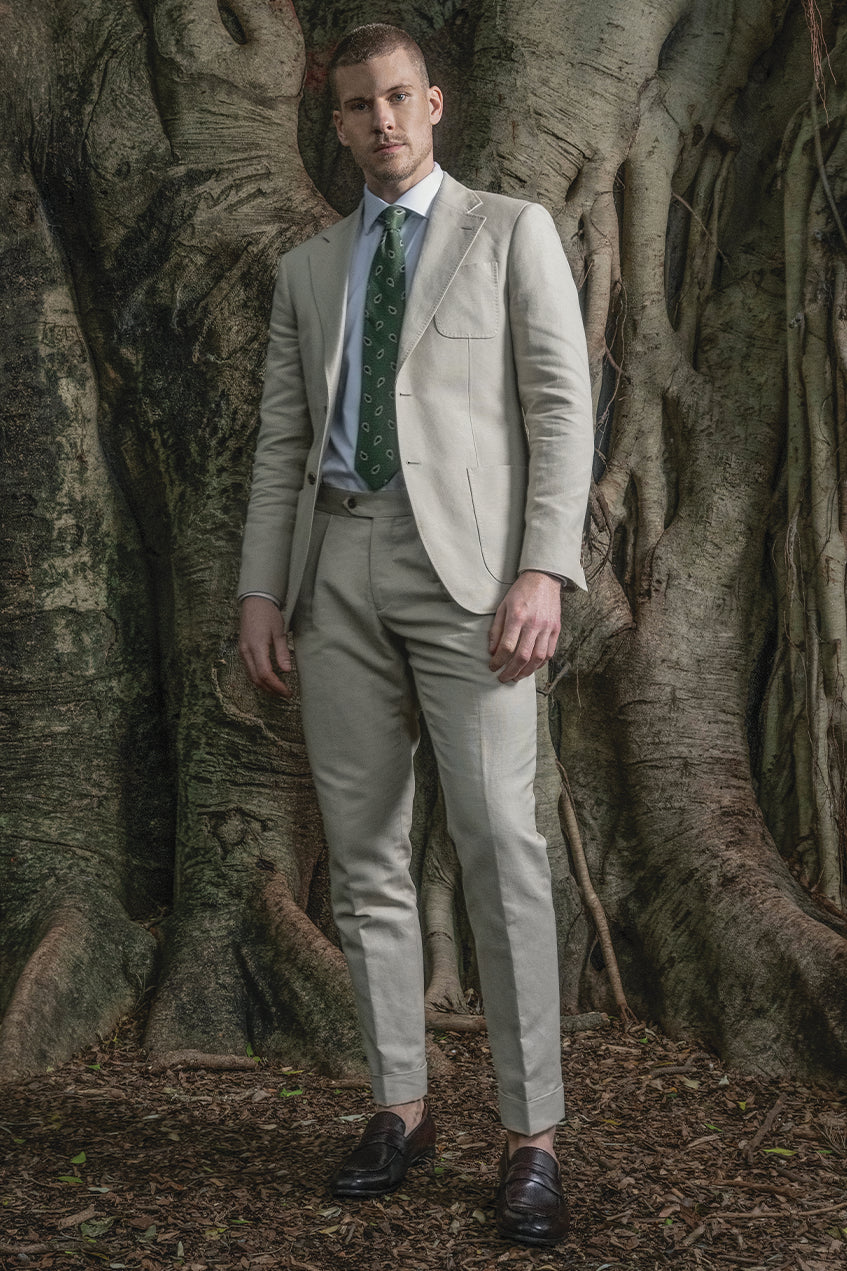 Man in a light gray suit standing in front of a large tree