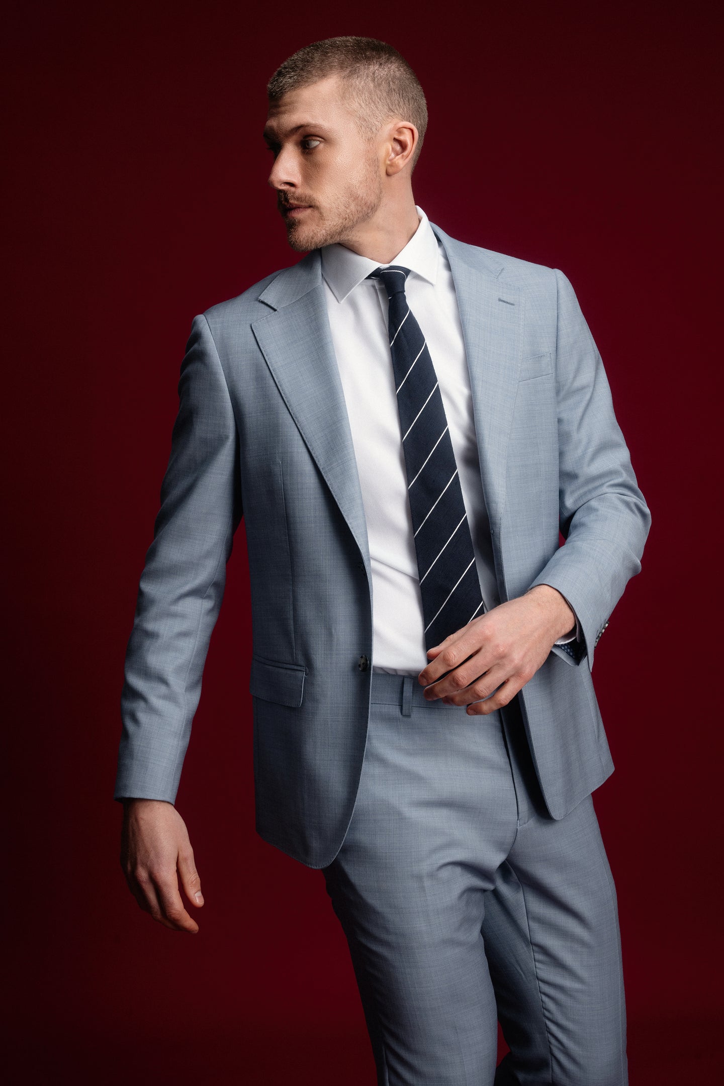 Man wearing a gray suit with a black tie against a red background