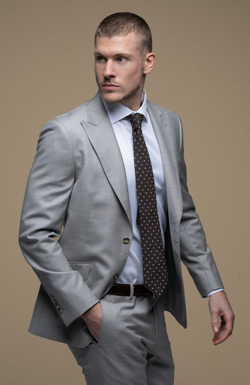 Man wearing a gray suit with a brown tie on a beige background