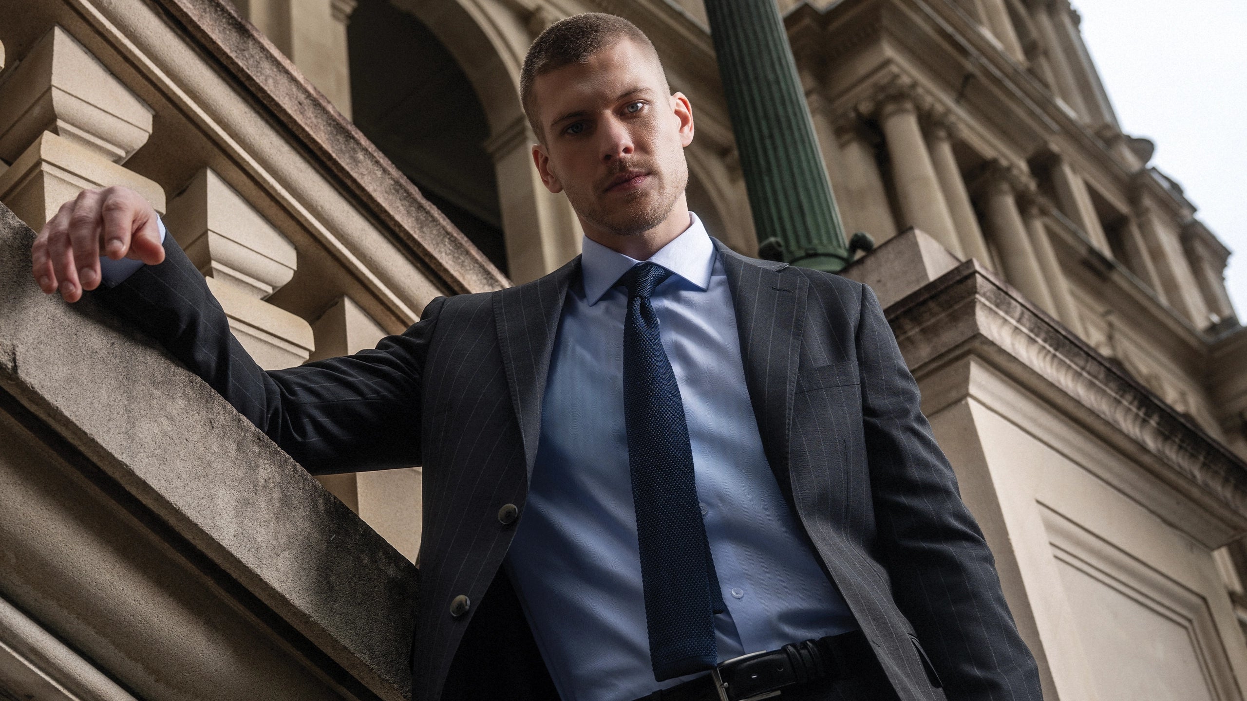 Man in a suit standing against an architectural background