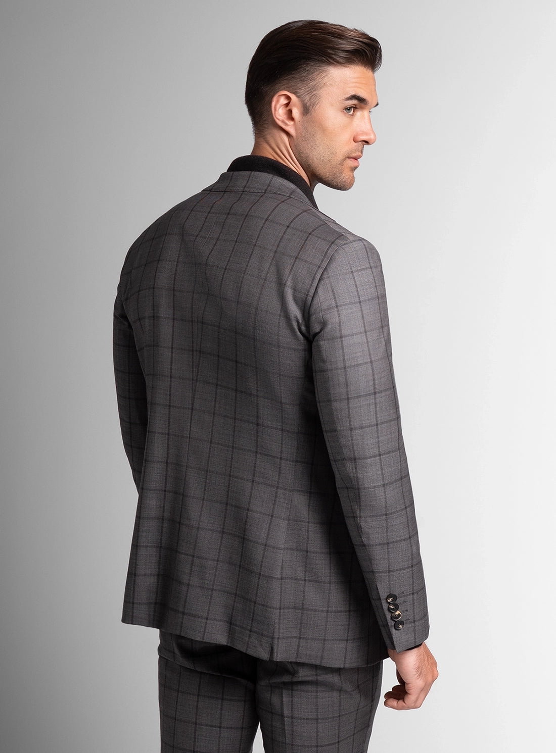 Man wearing a gray checkered suit jacket on a gray background