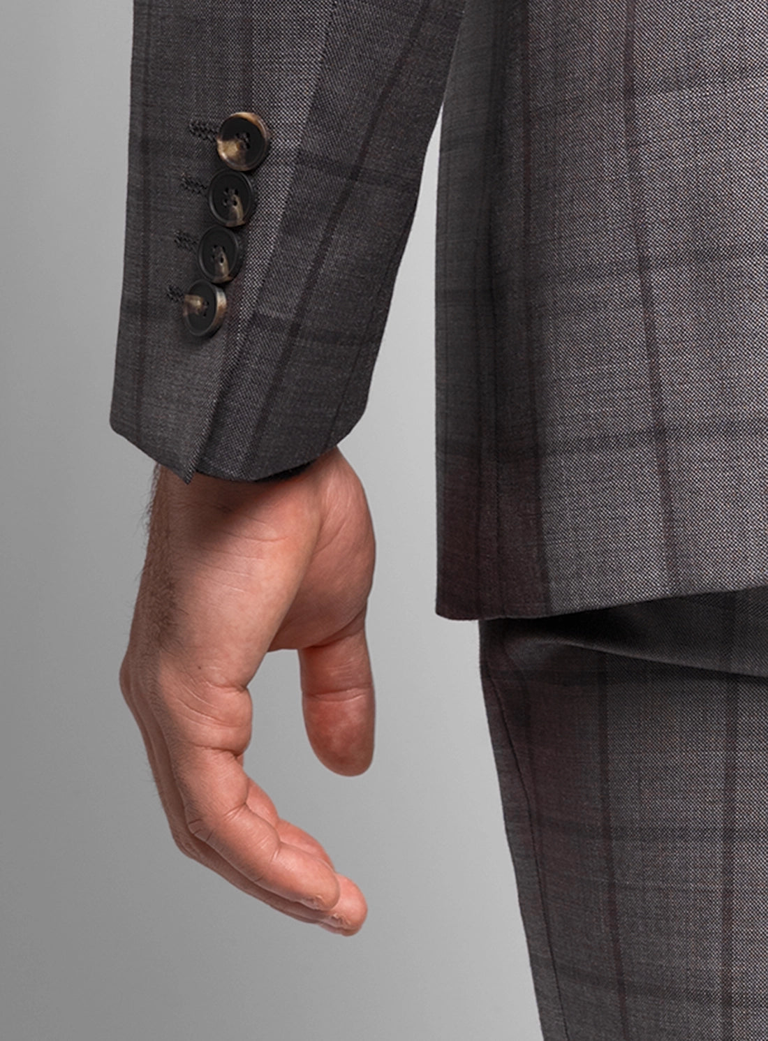 Gray checkered suit jacket with a hand holding it against a gray background