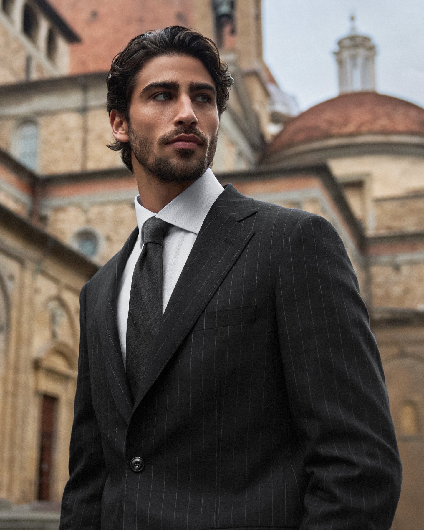 Man in a suit standing in front of an old architectural building