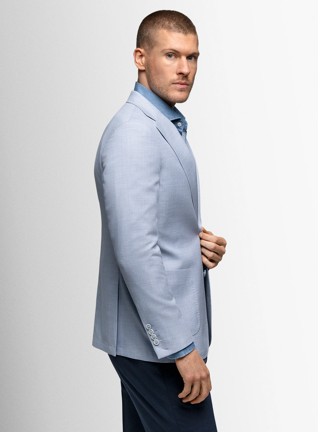 Man wearing a light blue blazer over a blue shirt on a white background