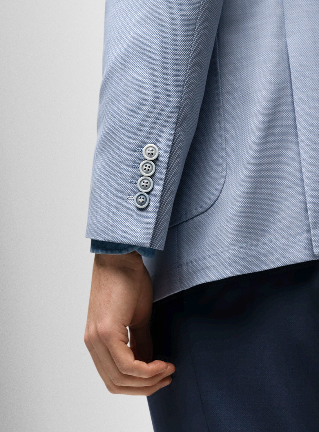 Close-up of a light blue blazer with buttons on a plain background
