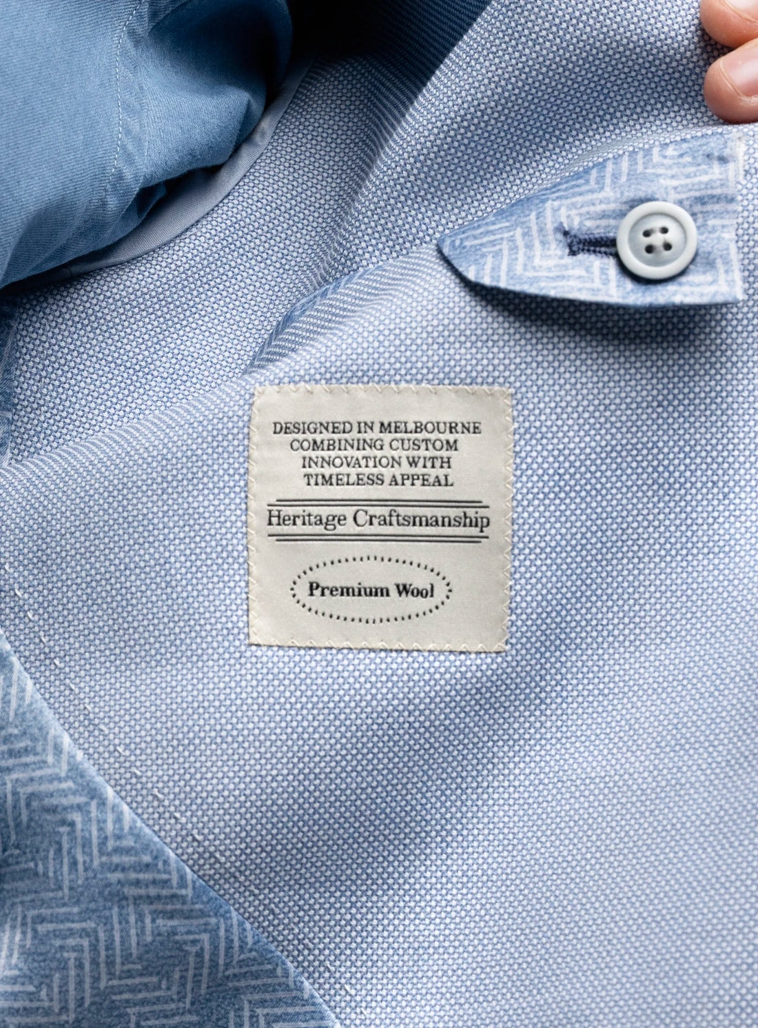 Close-up of a blue shirt with a label on the collar, featuring text about heritage craftsmanship.