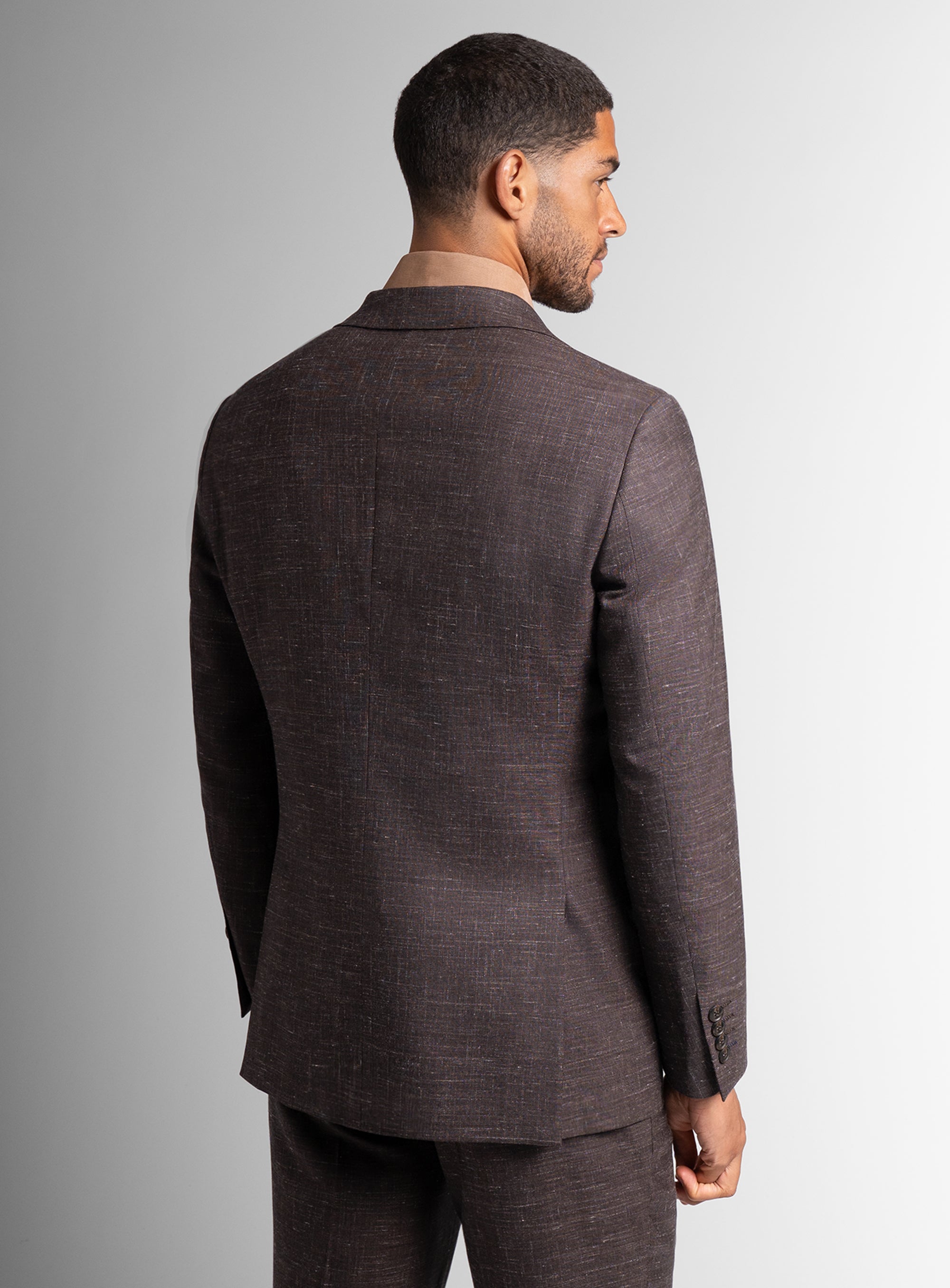 Man wearing a brown suit jacket on a gray background