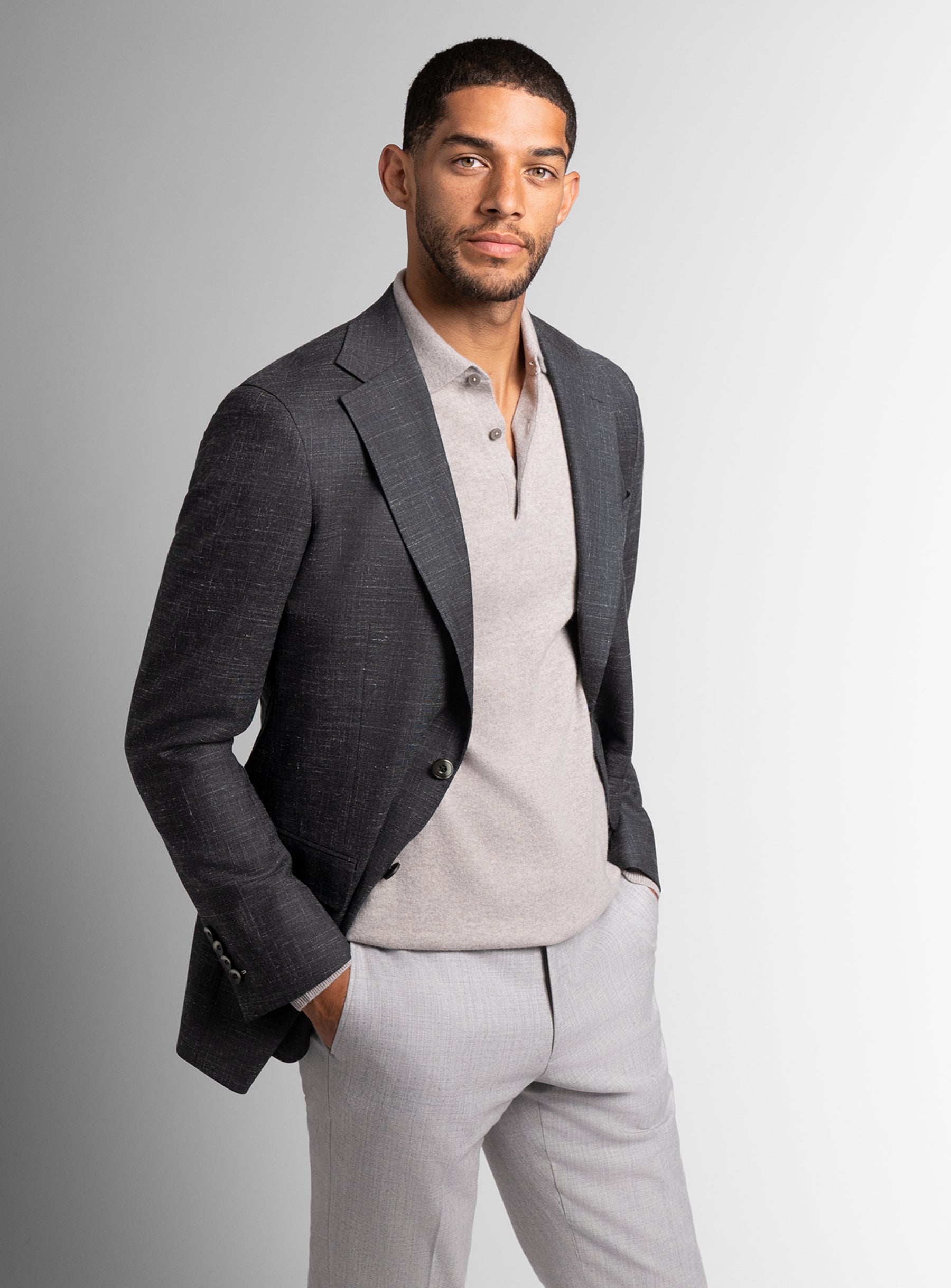 Man wearing a gray blazer over a light shirt and pants on a gray background