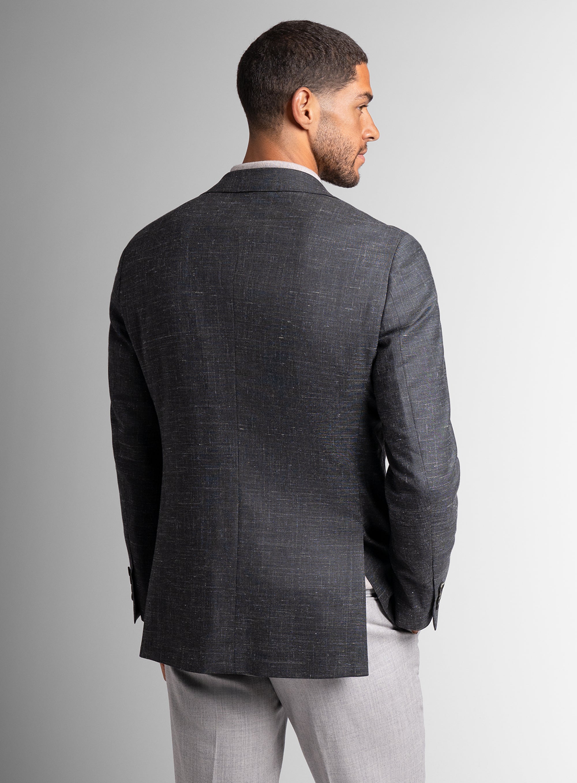 Man wearing a gray suit jacket and pants on a plain background