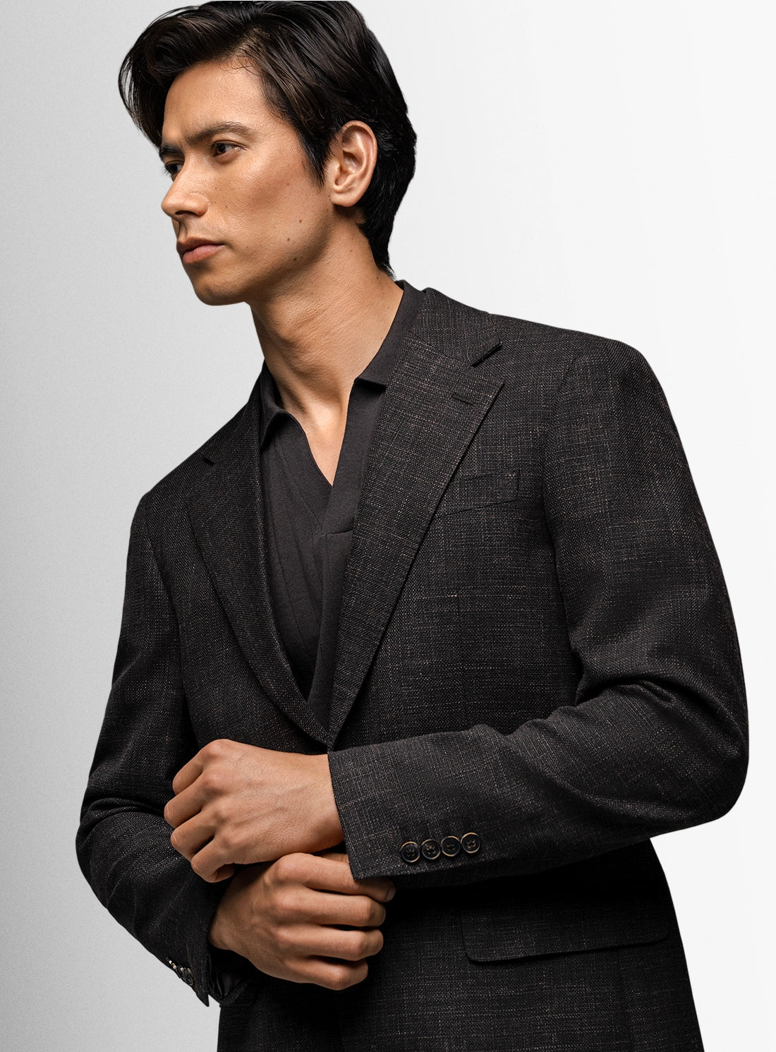 Man wearing a dark gray suit against a light gray background