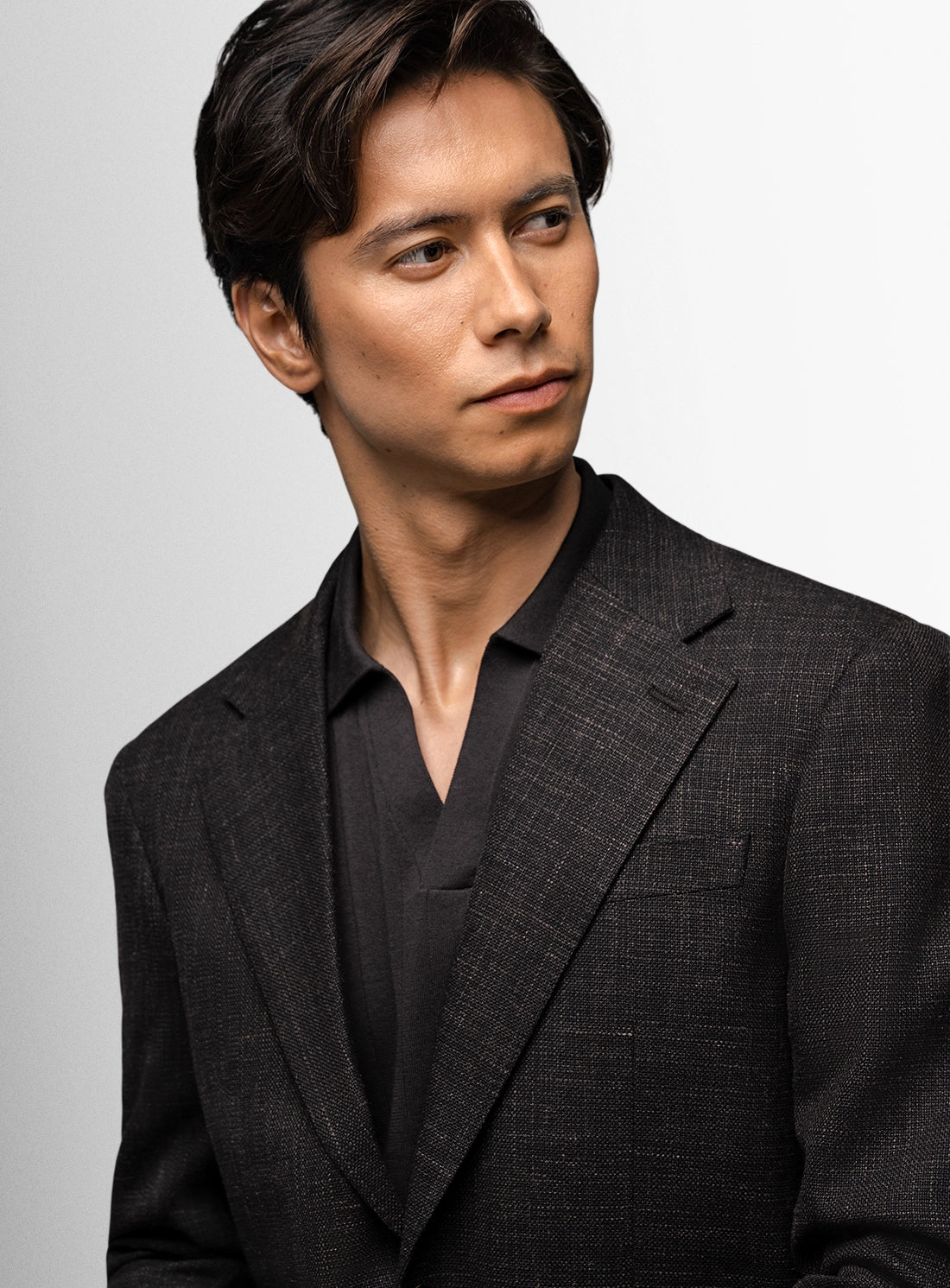 Man wearing a dark suit against a light gray background