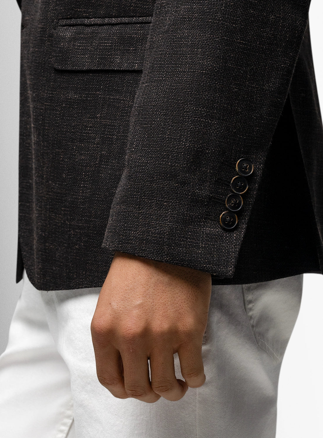 Close-up of a dark gray blazer with buttons and a white shirt.
