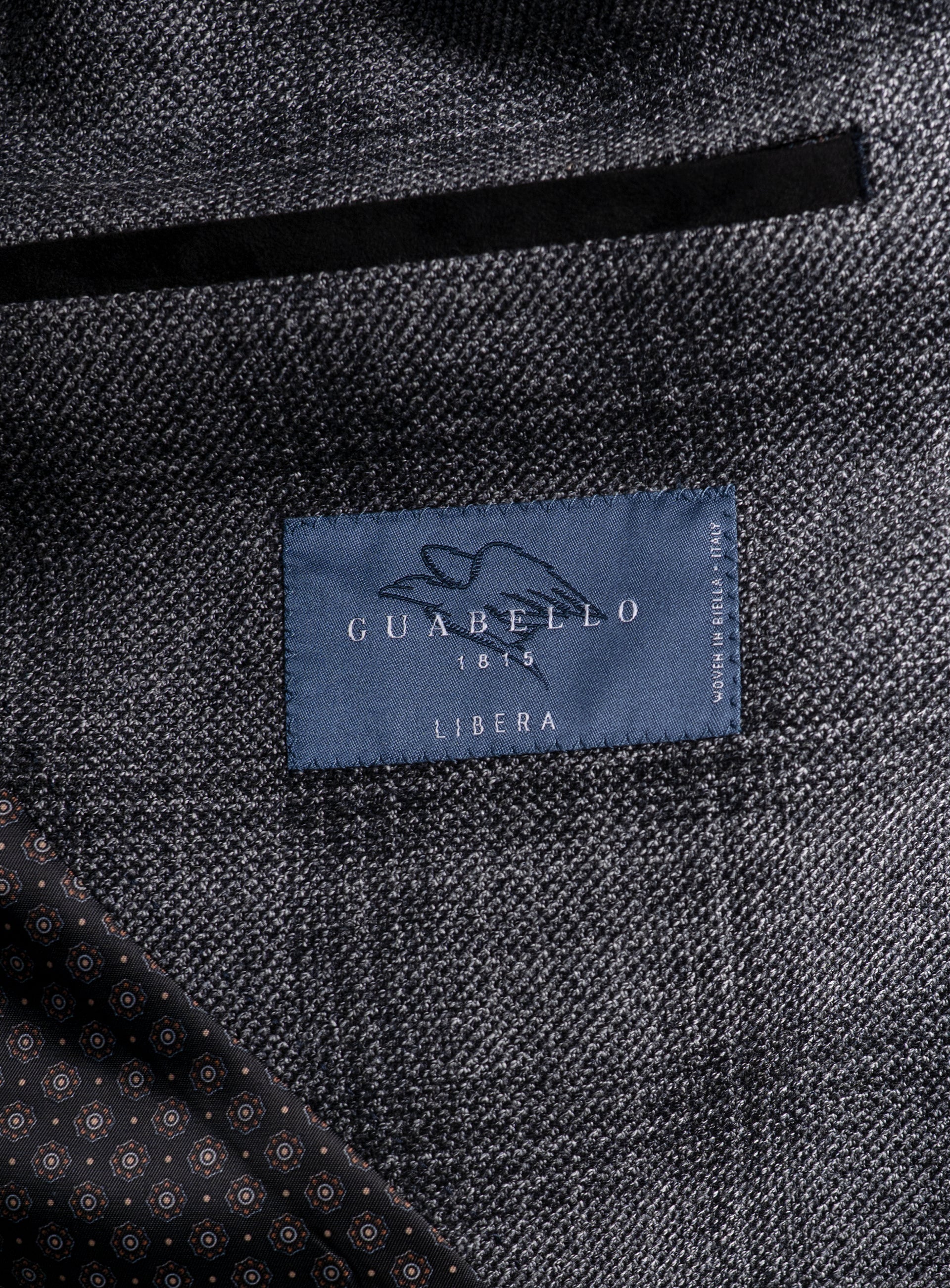 Picture of a label that says "Guabello 1815 Libera, Woven In Biella - Italy" on the Vitale Barleycorn Plaid Grey Sport Jacket