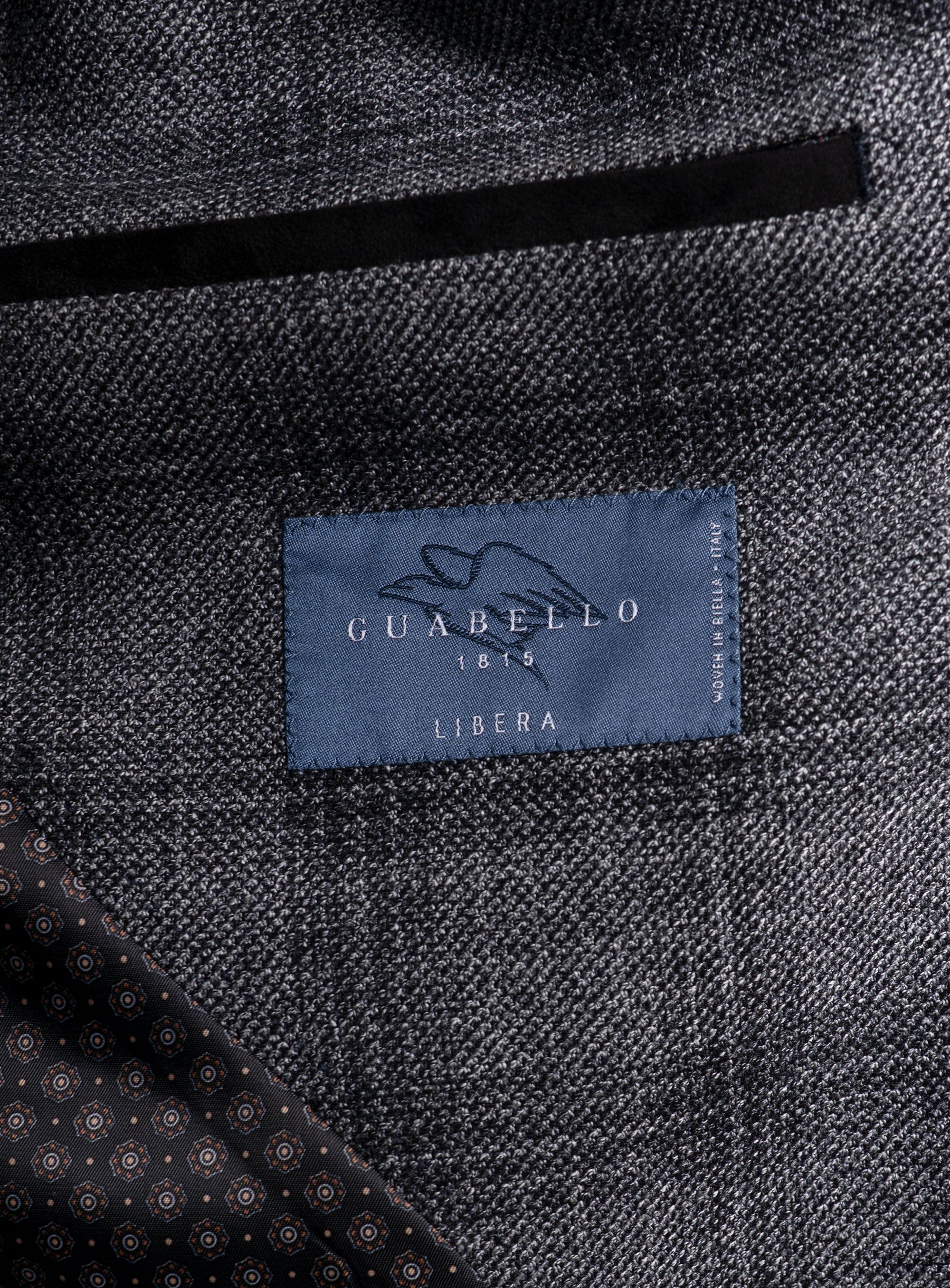 Picture of a label that says "Guabello 1815 Libera, Woven In Biella - Italy" on the Vitale Barleycorn Plaid Grey Sport Jacket
