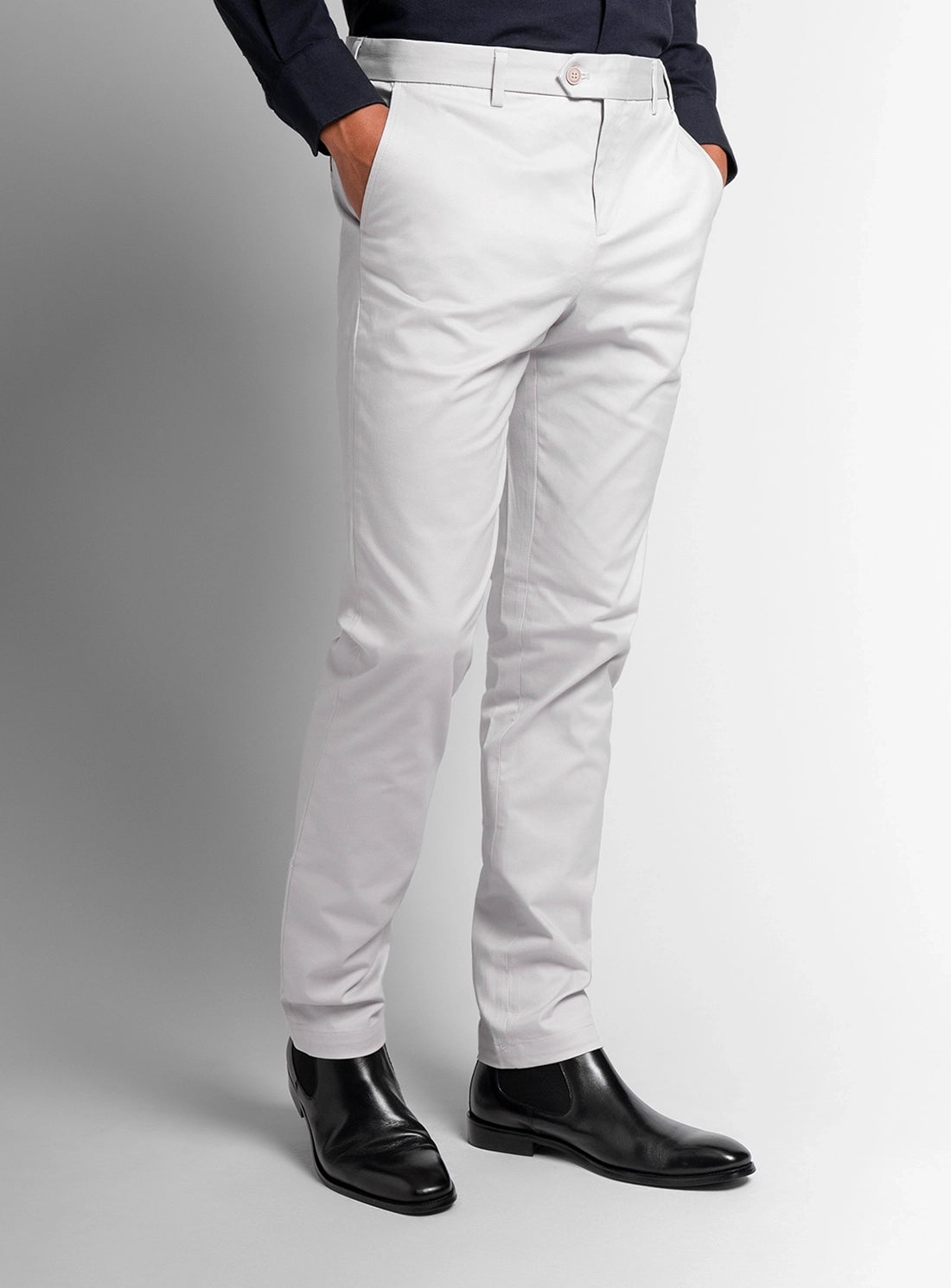 White dress pants worn by a person on a gray background