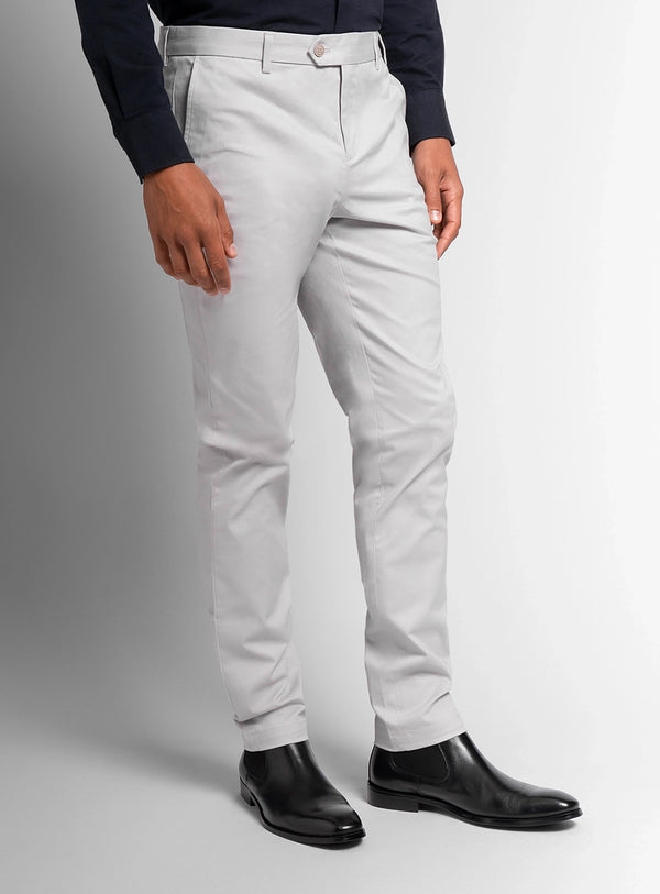 Person wearing light gray pants and black shoes on a plain background