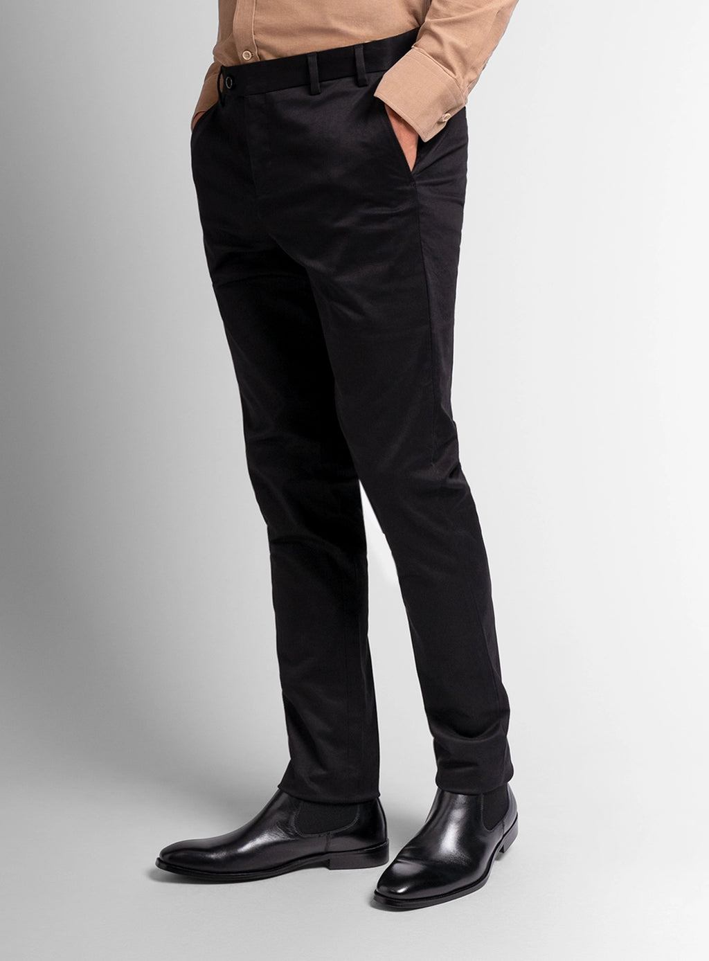 Person wearing black pants and black shoes on a light gray background