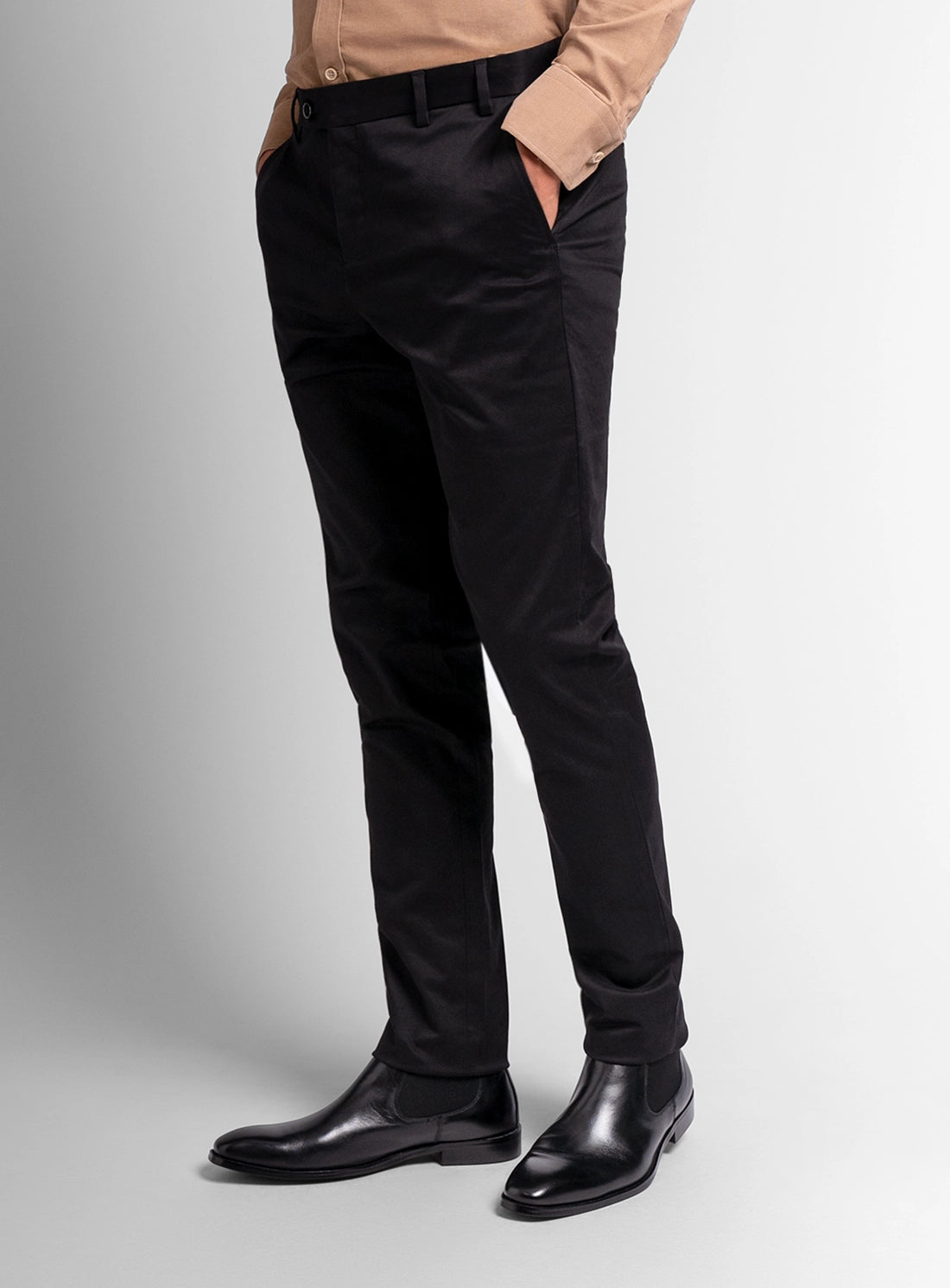 Person wearing black pants and black shoes on a light gray background