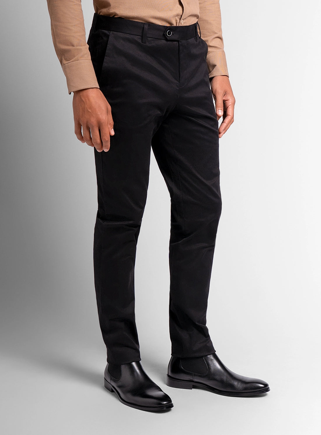 Person wearing black pants and black shoes on a gray background
