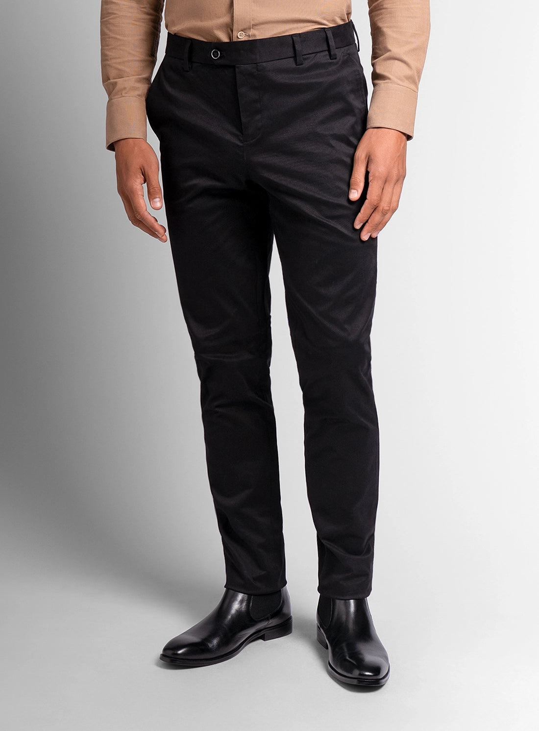 Person wearing black pants and black shoes on a gray background