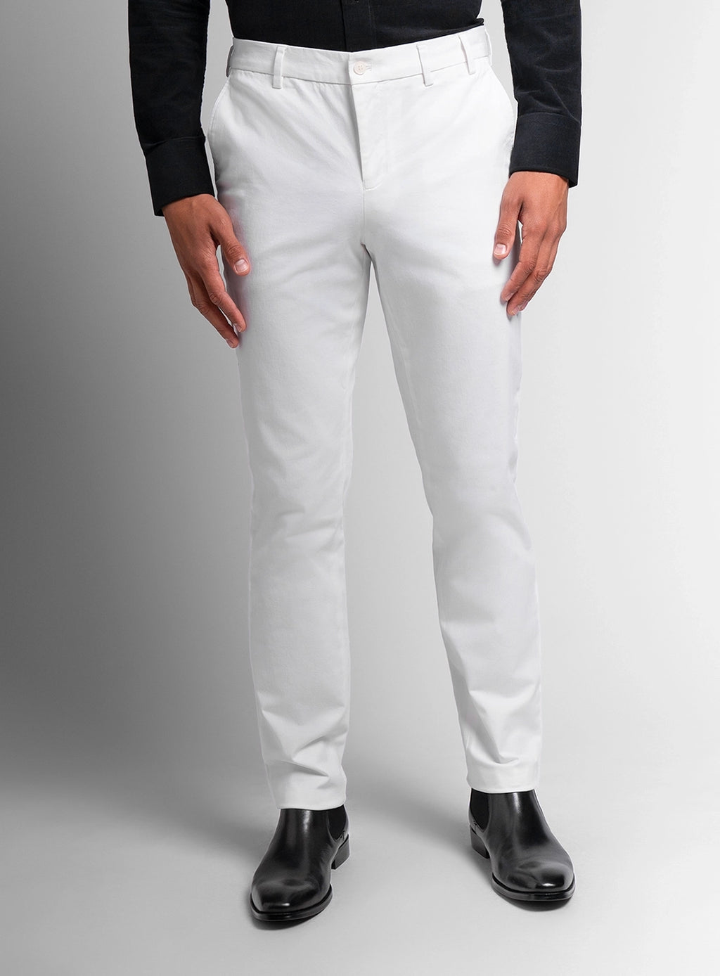 Person wearing white dress pants with a black shirt on a gray background