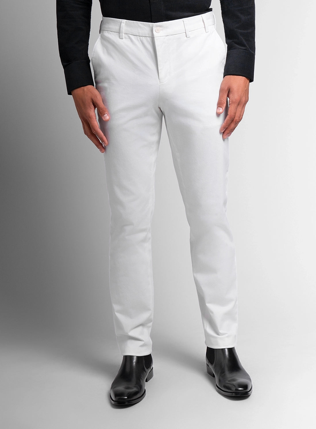 Person wearing white dress pants with a black shirt on a gray background