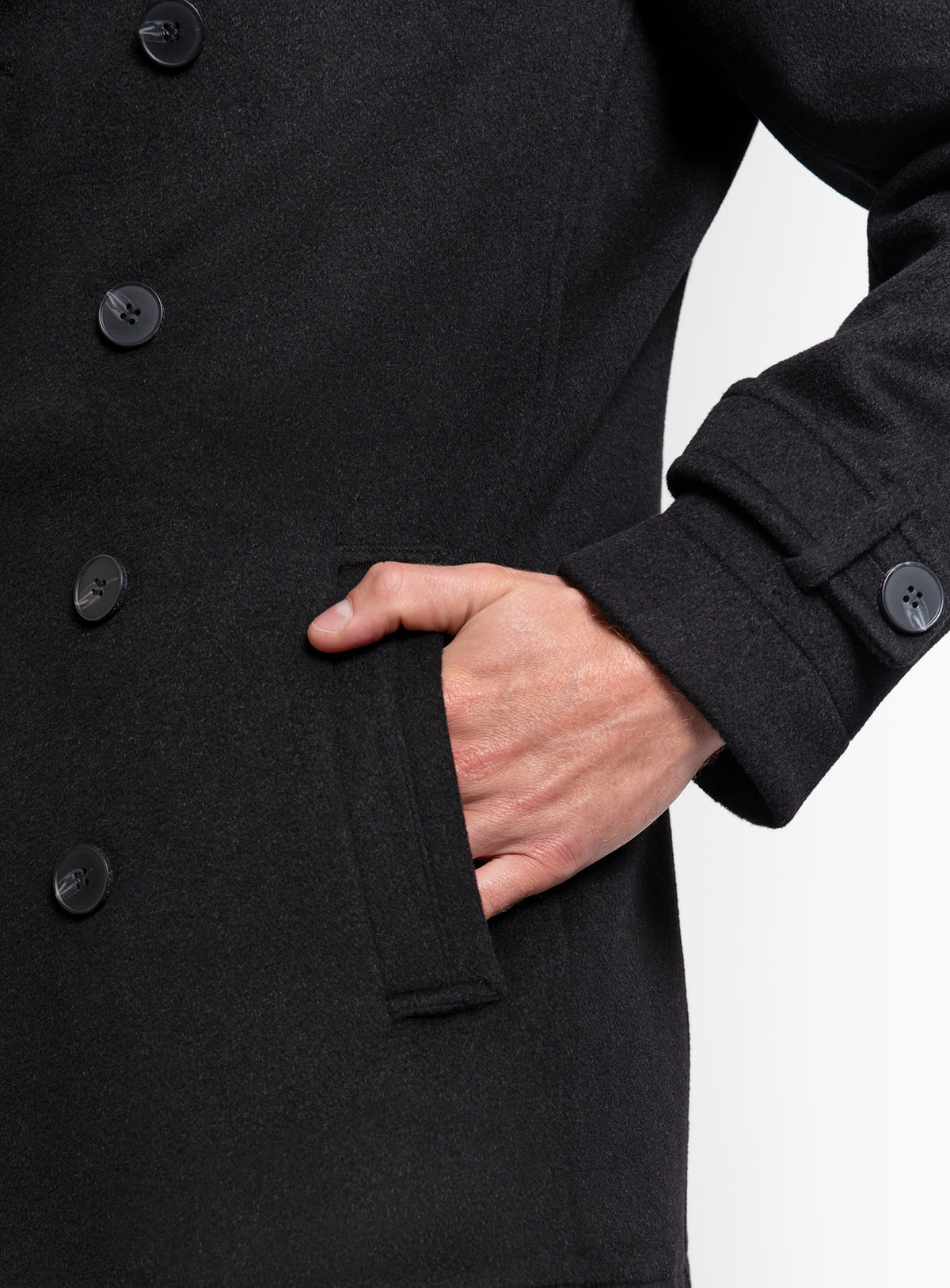 A man with his hand in his pocket, wearing the Bridge Black Peacoat