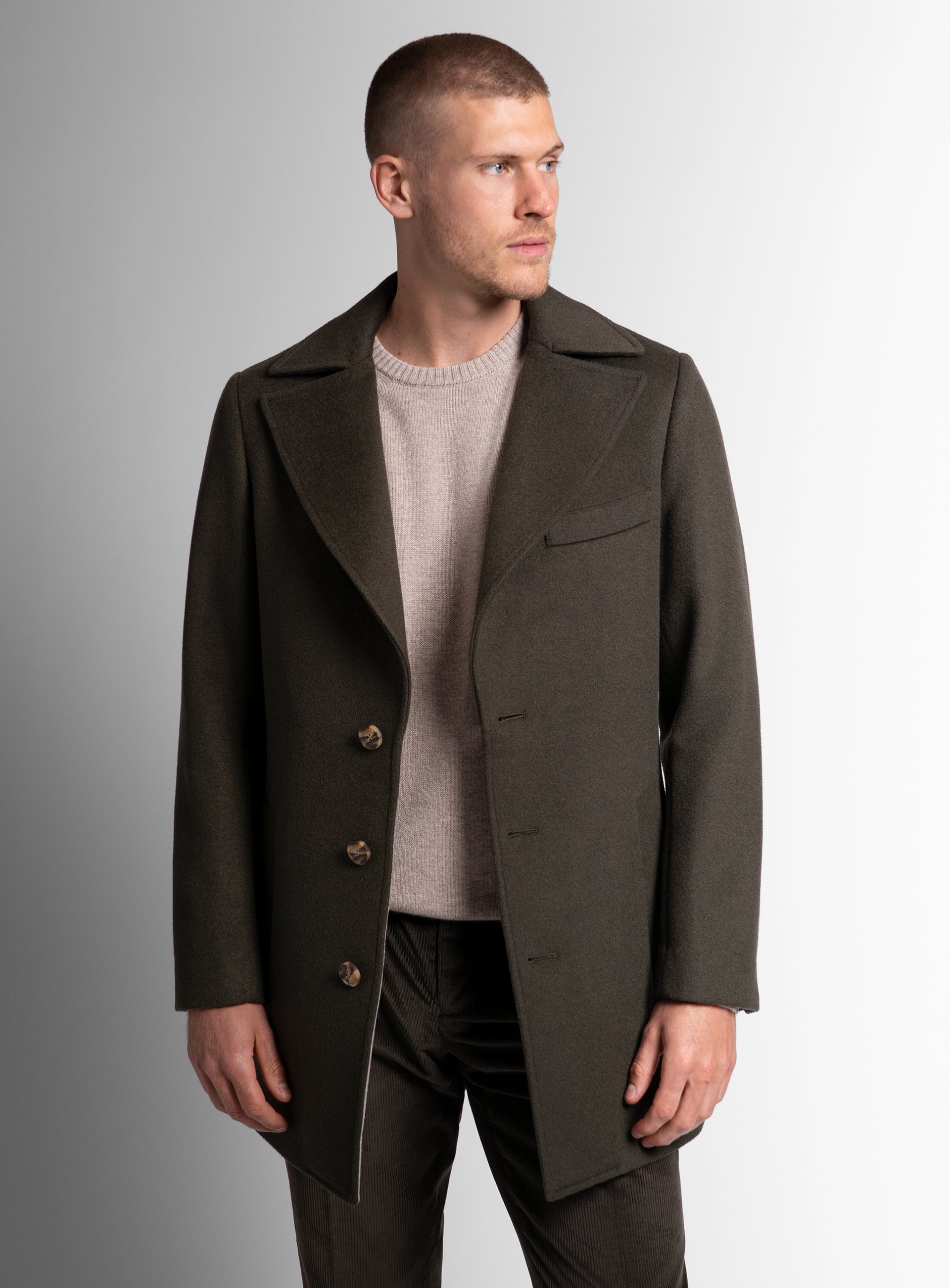 A man looking to his side wearing the Gallio Wool Pile Forest Green Coat