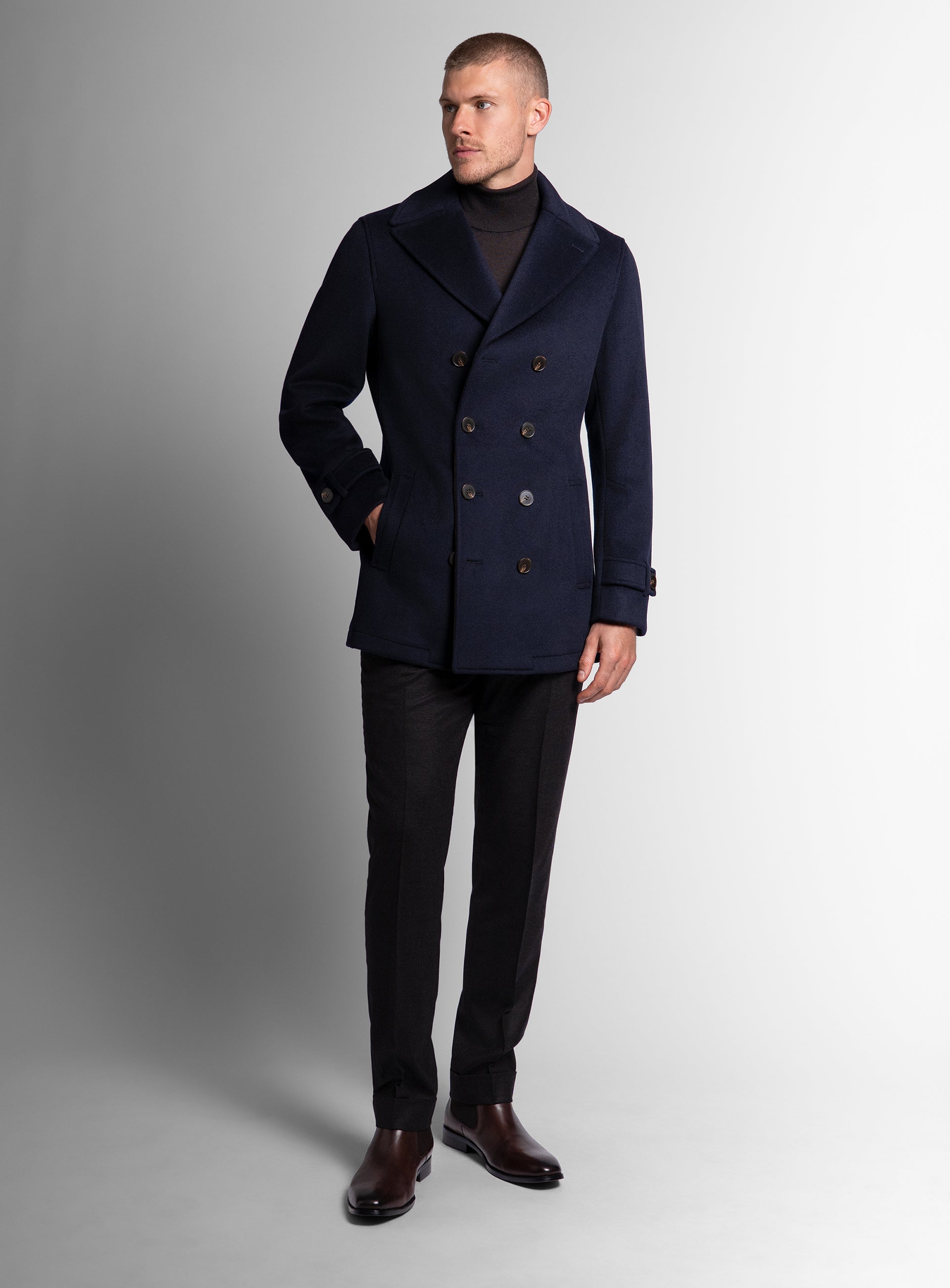 A man wearing the Bridge Navy Blue Peacoat with his hand in his pocket