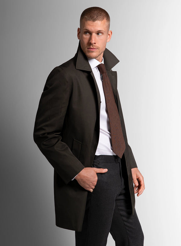 Man wearing a dark coat and tie against a gray background