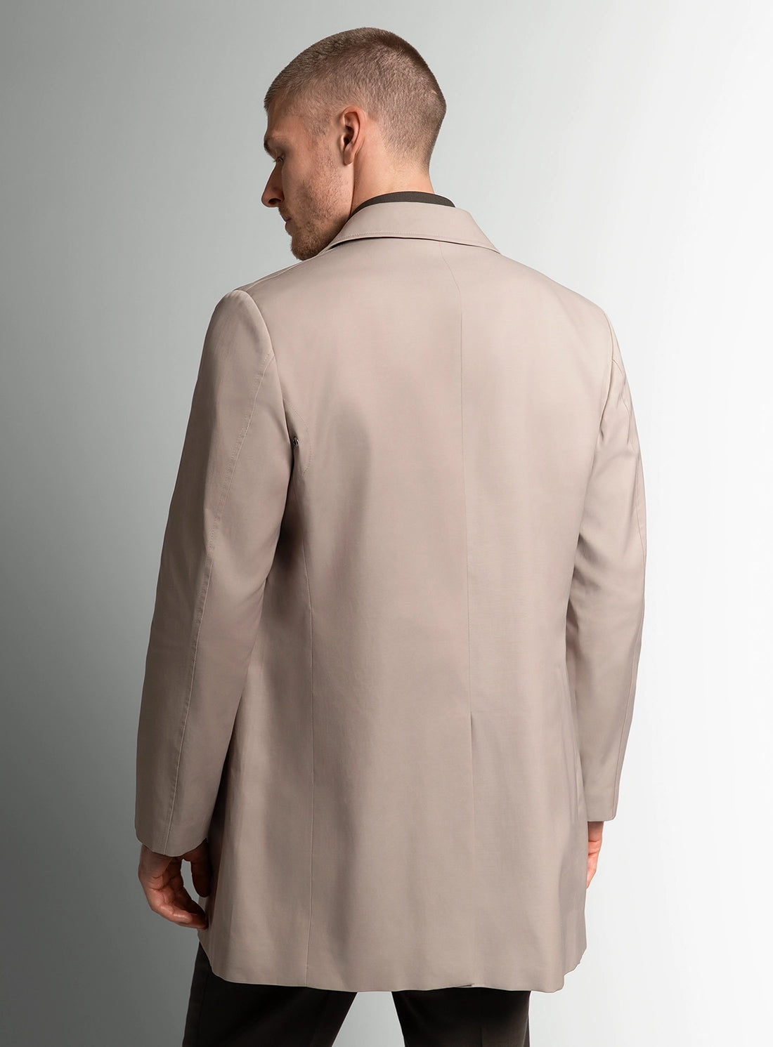 Man wearing a beige coat against a plain background