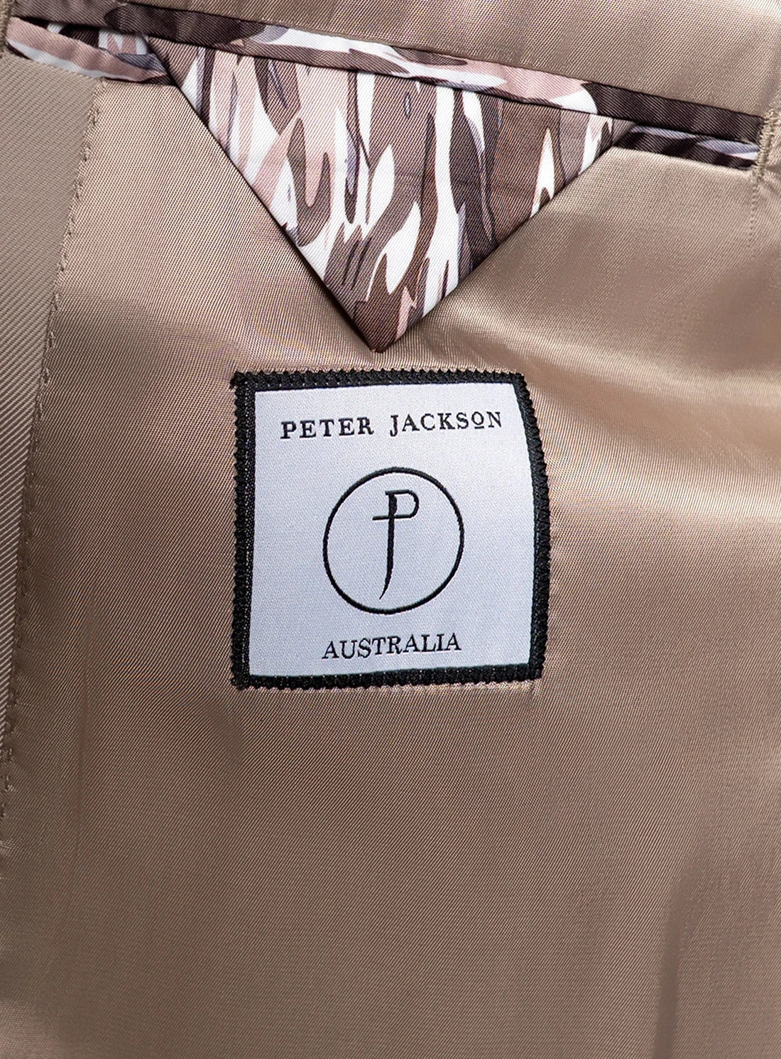 Close-up of a beige fabric with a Peter Jackson Australia label and camouflage patterned lining.