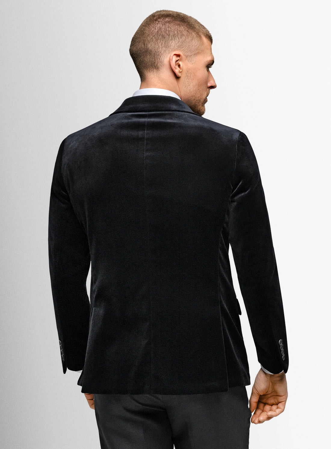 Man wearing a black velvet blazer on a plain background