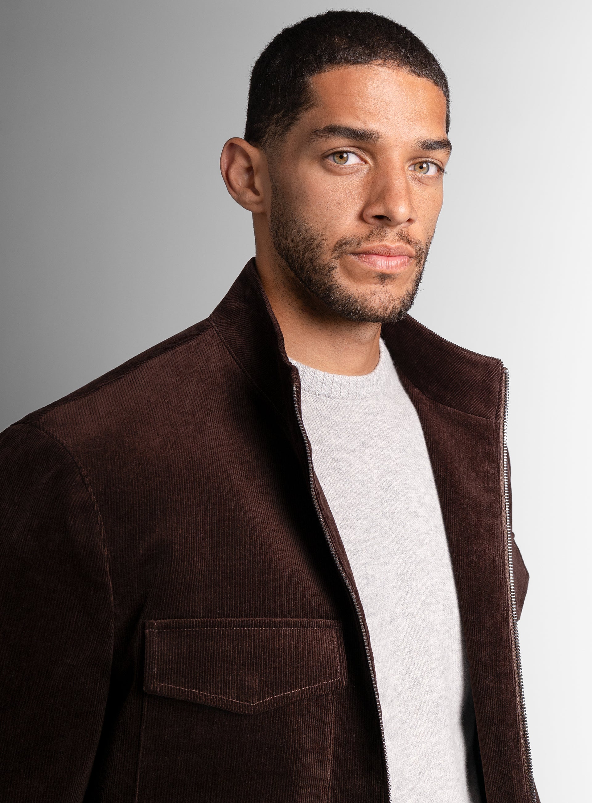 A close-up of a man looking to his side wearing the Aldor Corduroy Chocolate Brown Jacket