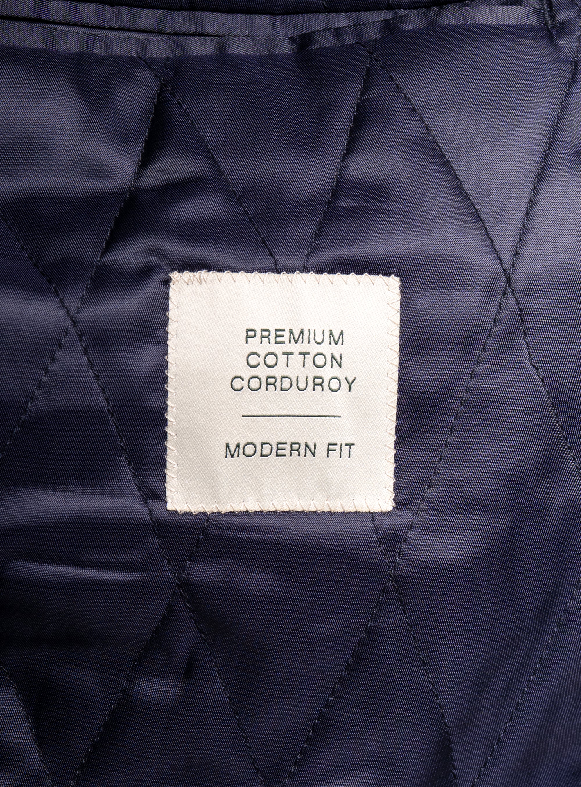 A label that says "Premium Cotton Corduroy - Modern Fit" on the Aldor Corduroy Chocolate Brown Jacket