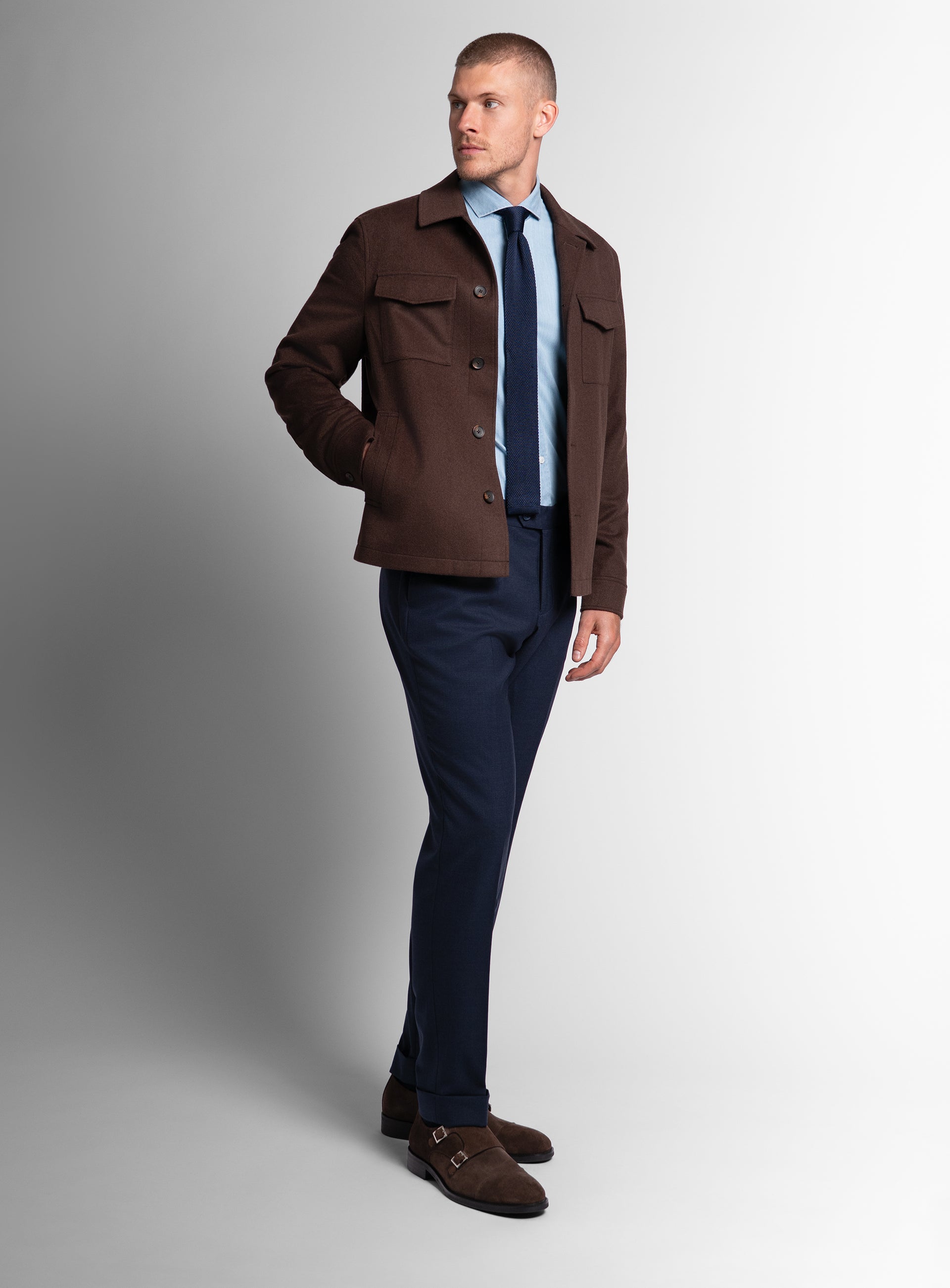 A man looking to his side with his hand in his pocket while wearing the Orlando Chocolate Brown Jacket