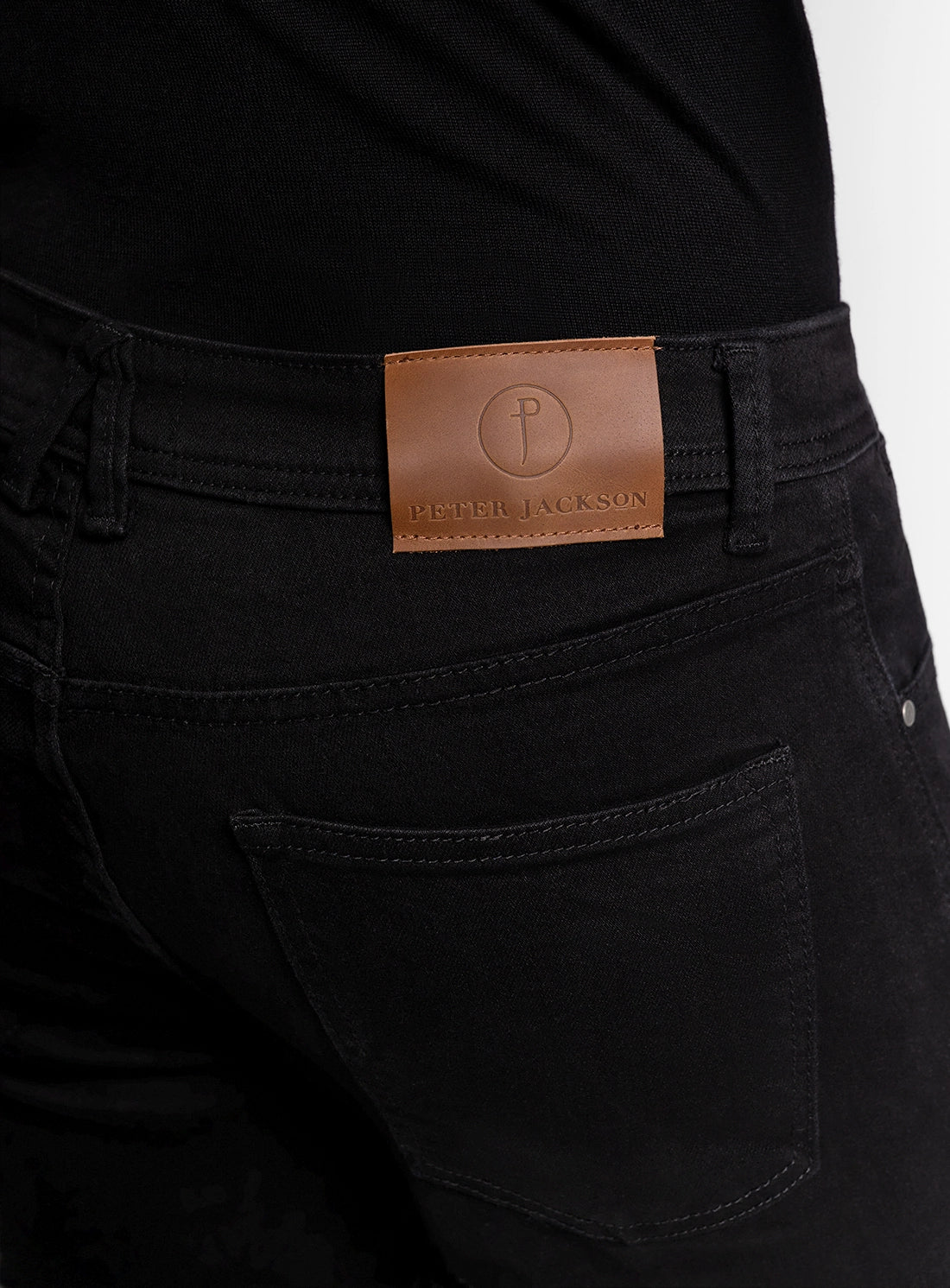 Black pants with a brown leather label on a black background