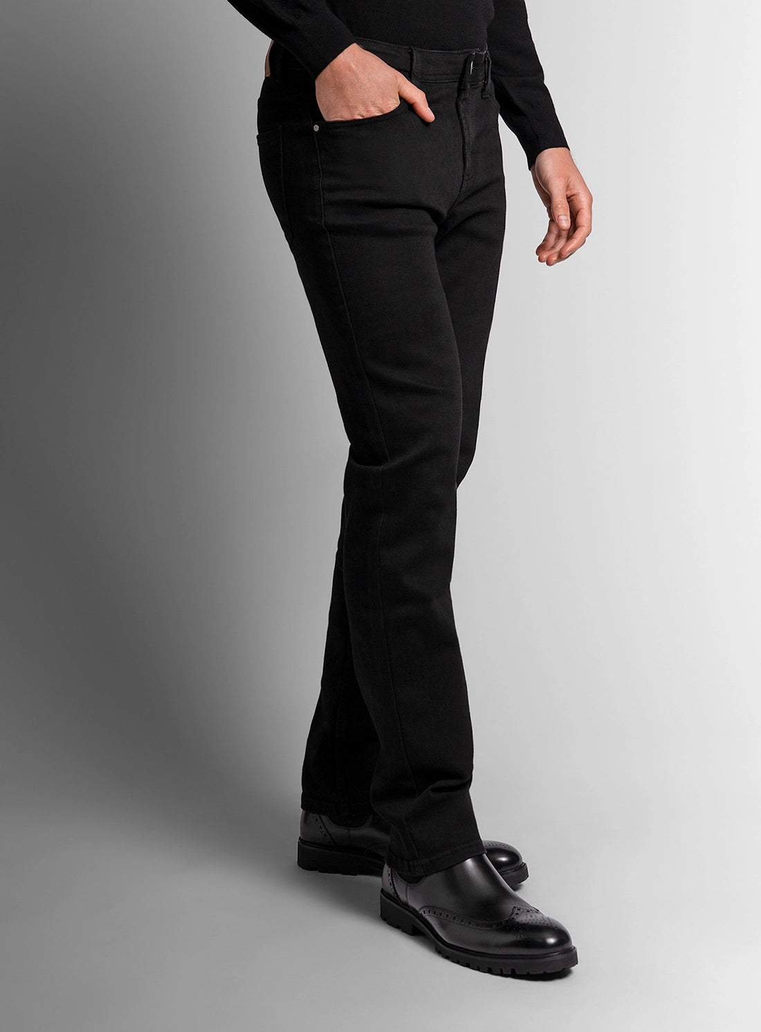 Person wearing black pants and shoes on a gray background