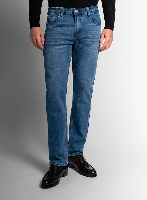 Person wearing blue jeans and black shoes on a gray background