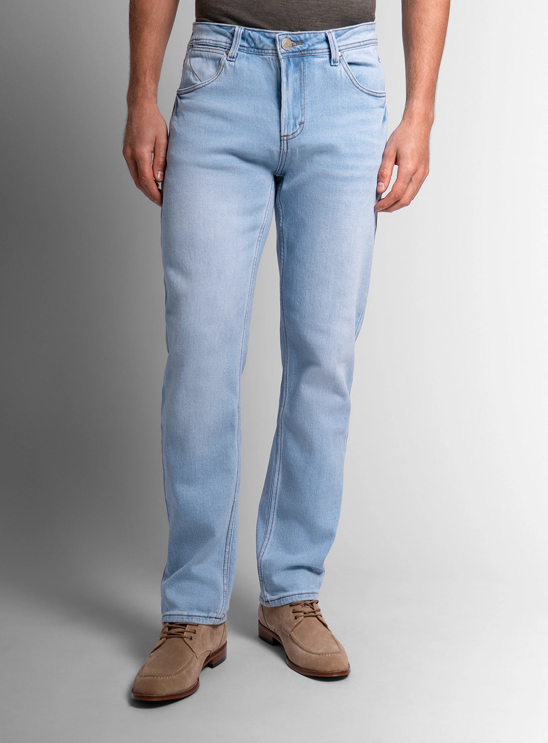 Person wearing light blue jeans on a gray background