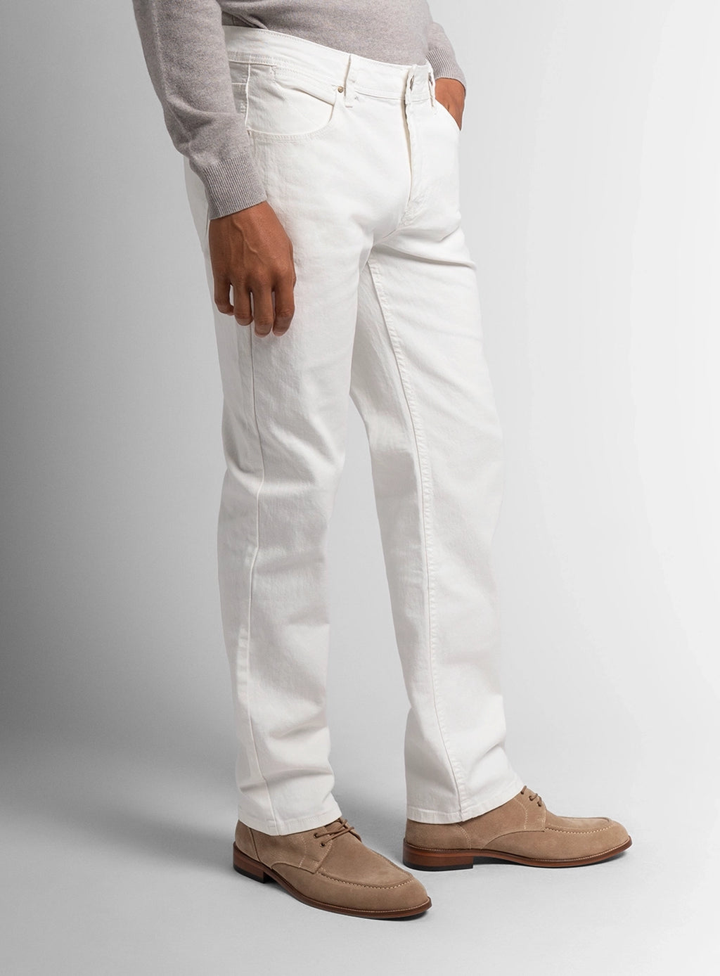 Person wearing white pants and brown shoes on a gray background