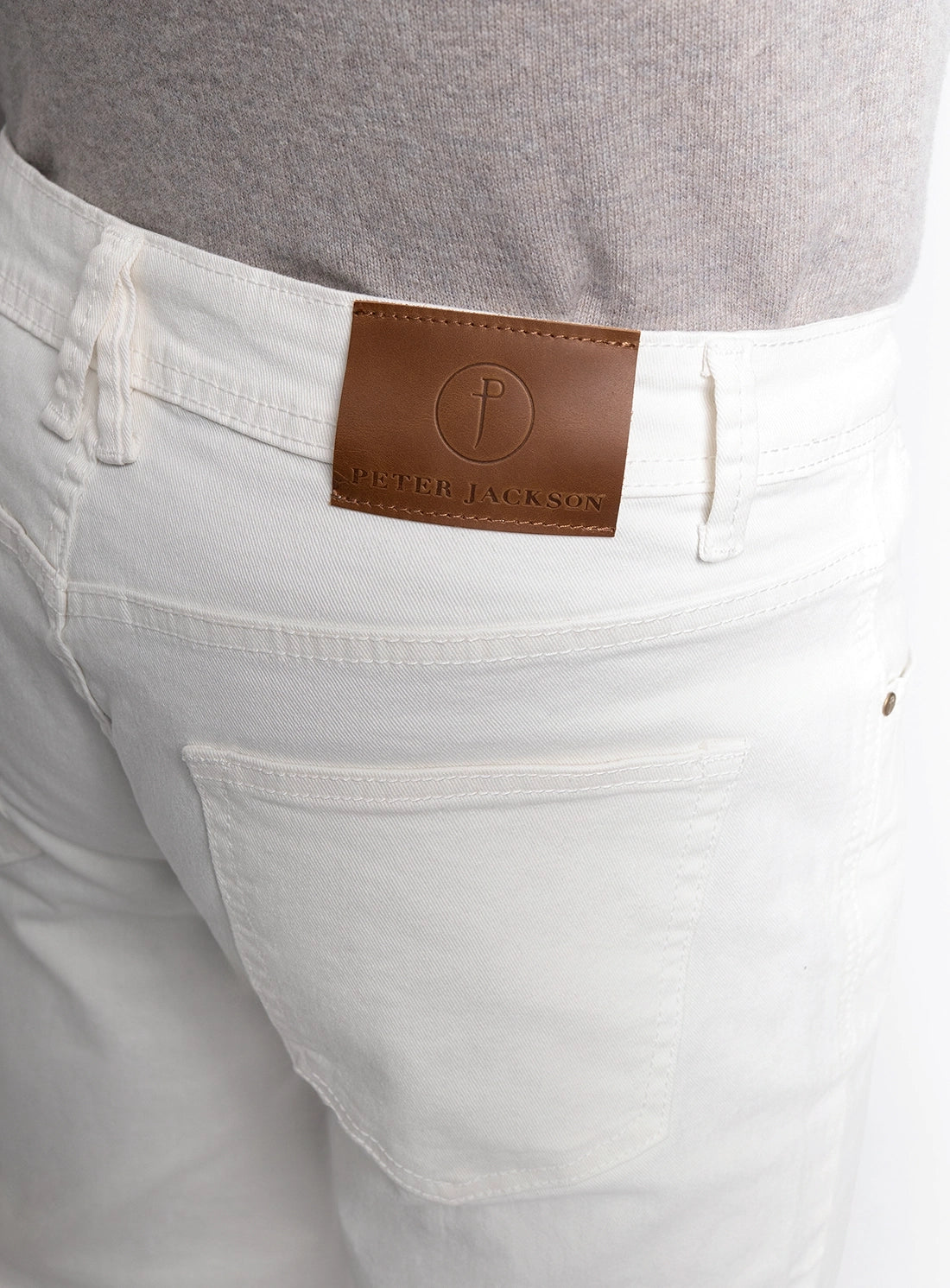 White pants with a brown leather patch and brand logo on a gray background