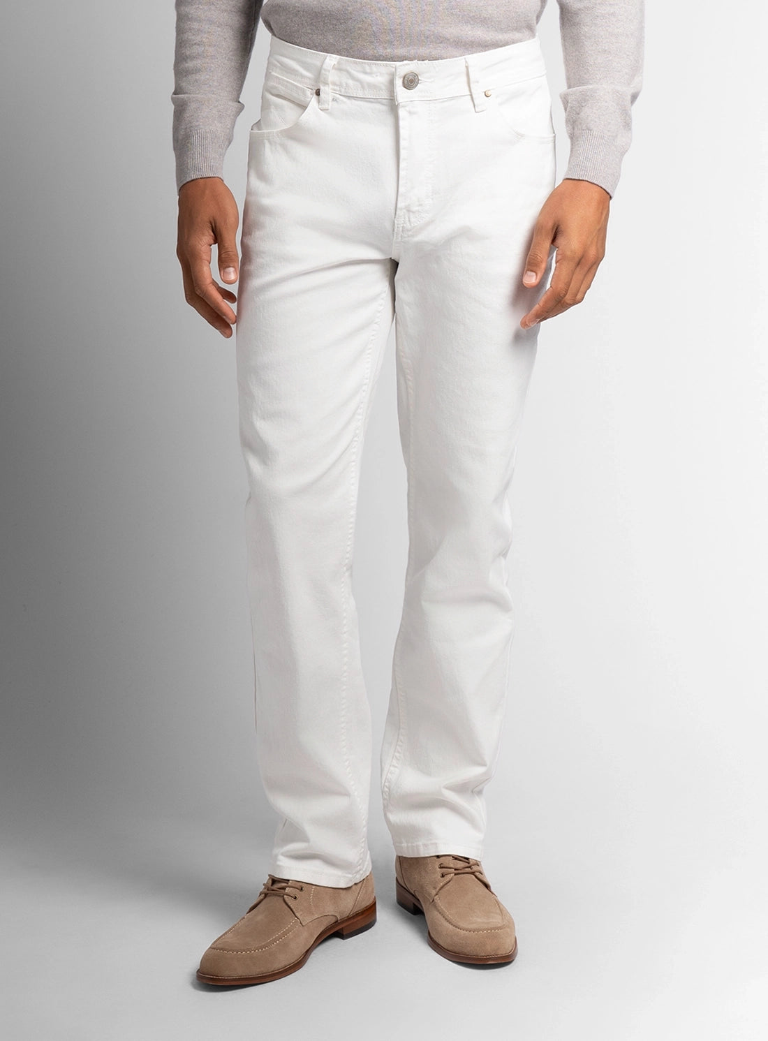 Person wearing white pants and brown shoes on a gray background