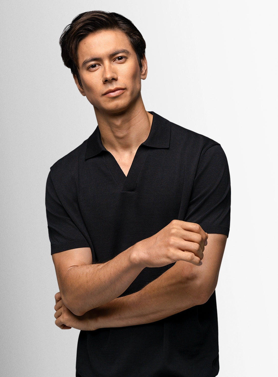 Man wearing a black polo shirt against a gray background