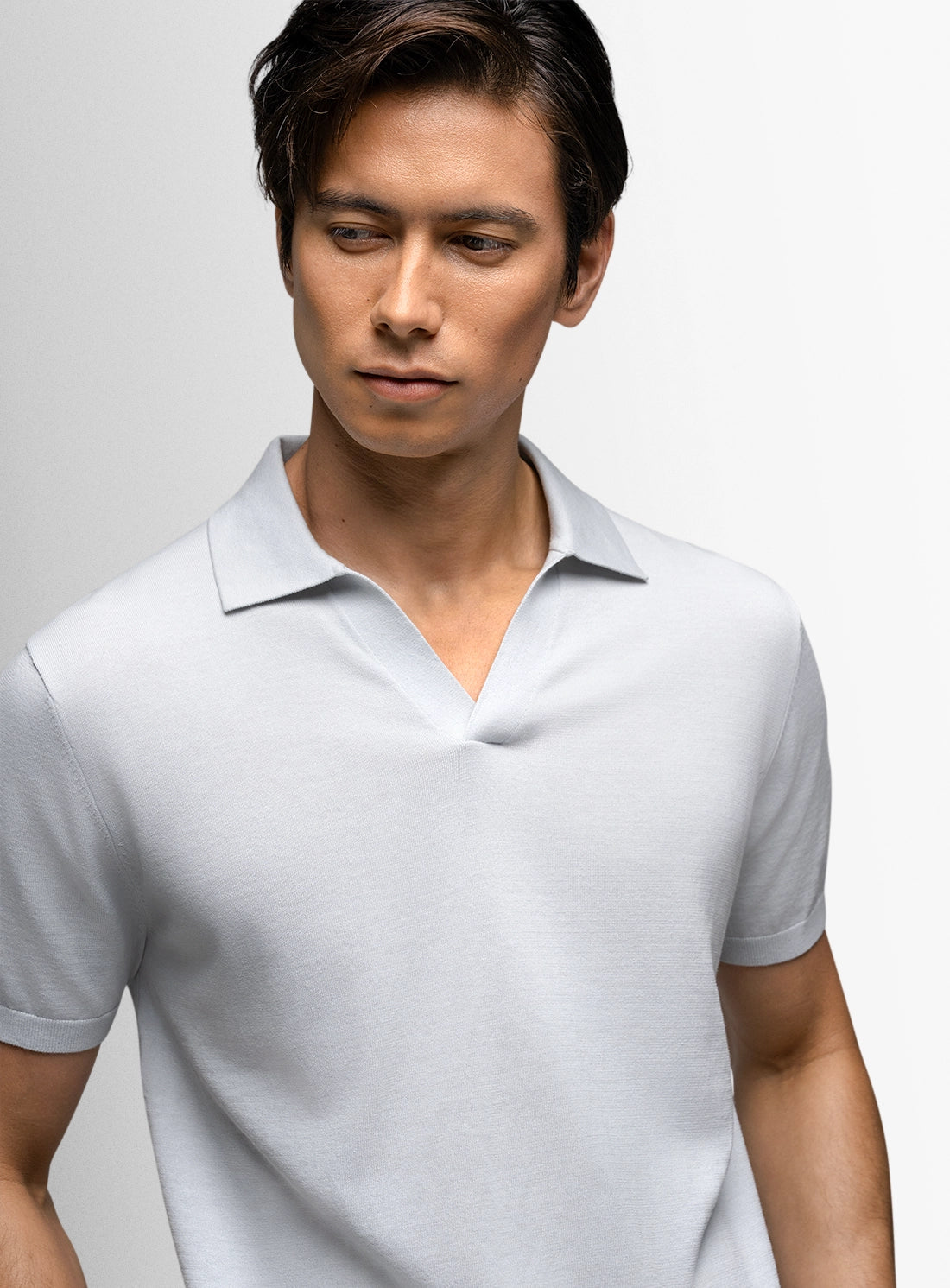 Man wearing a light gray polo shirt against a plain background